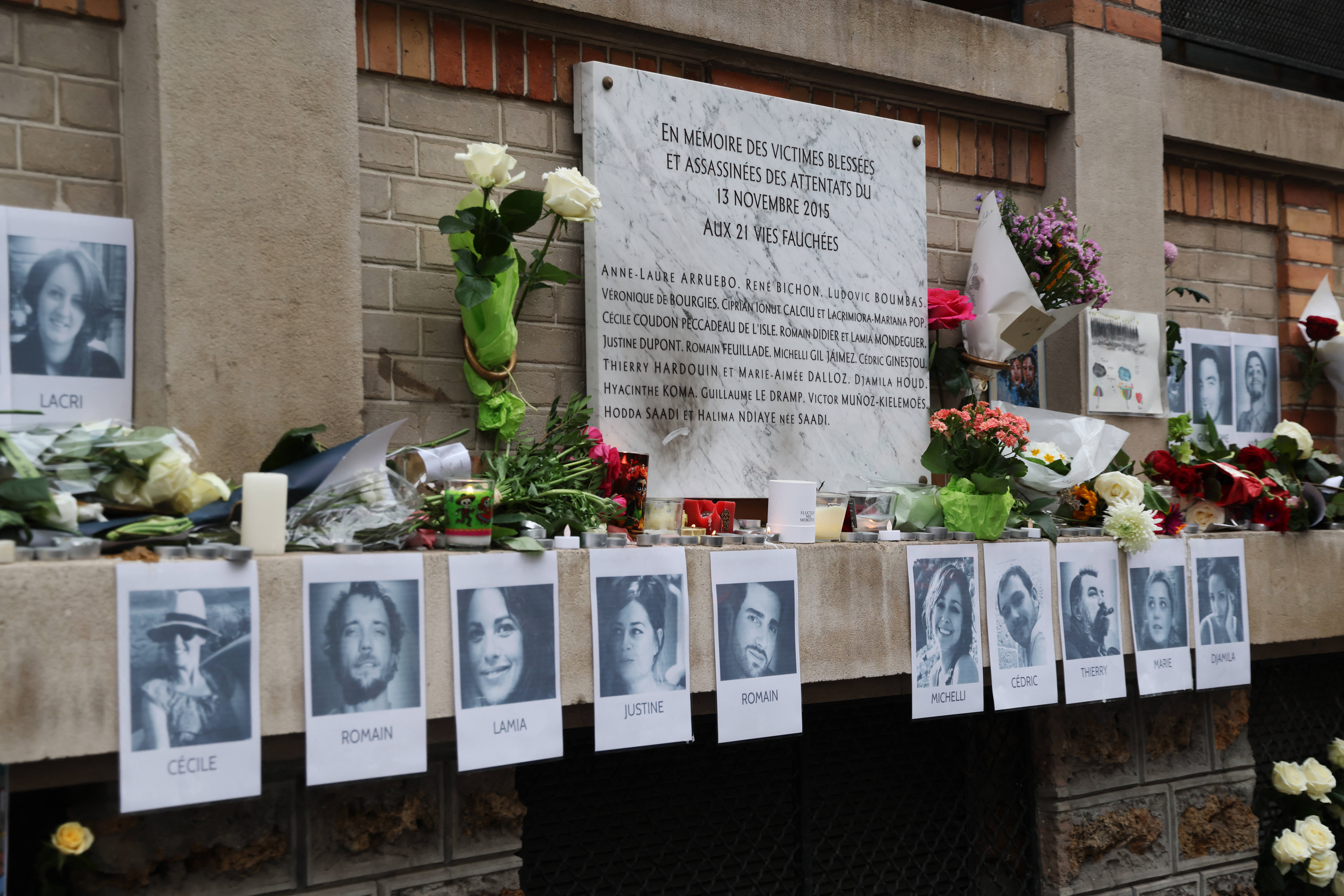 CORRECTION / This photograph shows pictures of victims and flowers placed next to a commemorative plaque outside "La Belle Equipe" bar in Paris on November 13, 2025 during ceremonies across Paris marking a decade since the terror attacks of November 13, 2015 in which 130 civilians were killed. (Photo by Ludovic MARIN / POOL / AFP)