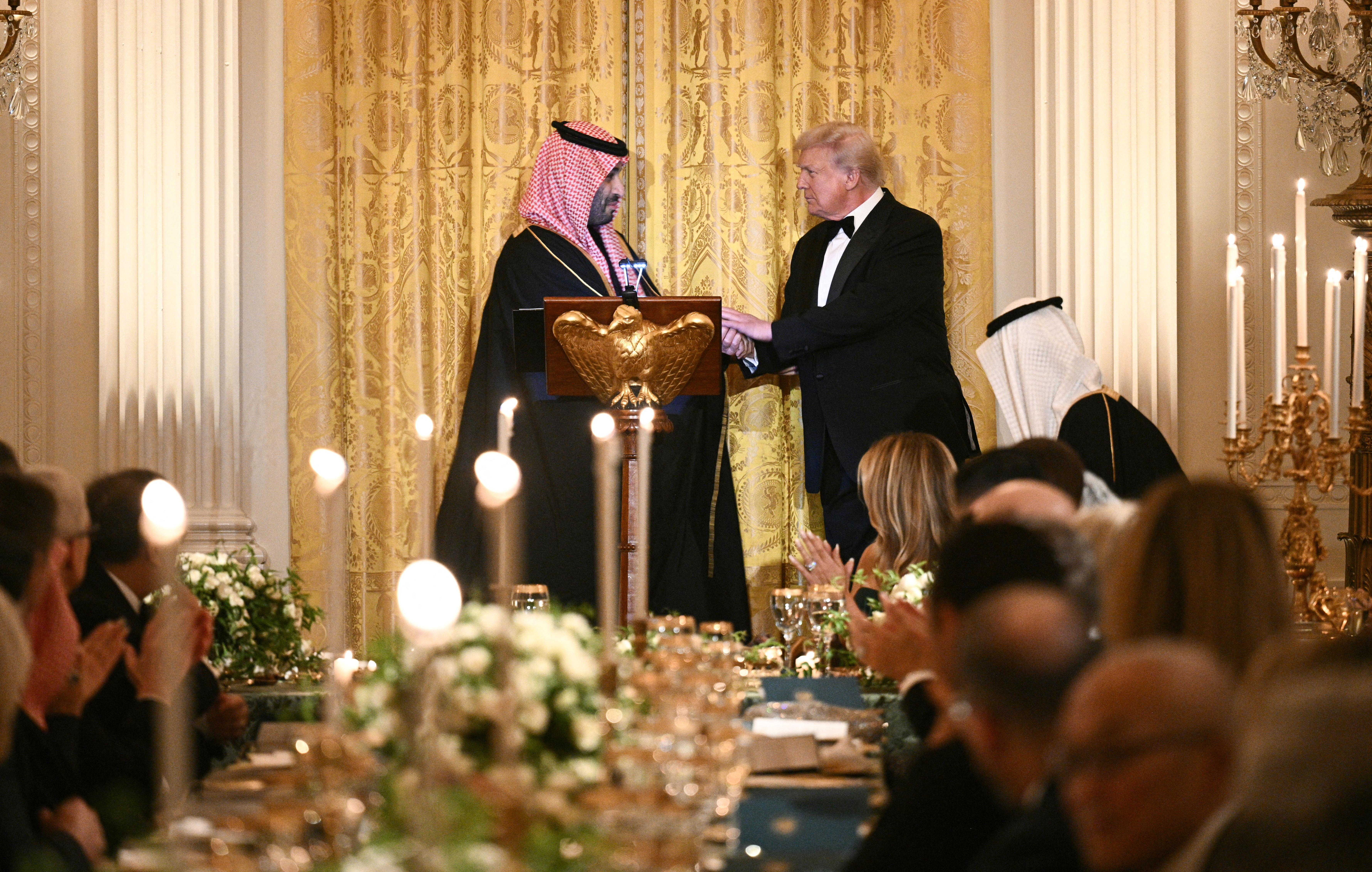 US President Donald Trump (R) shakes hands with Crown Prince and Prime Minister of the Kingdom of Saudi Arabia Mohammed bin Salman during an official dinner in the East Room of the White House in Washington, DC on November 18, 2025. (Photo by Brendan SMIALOWSKI / AFP)