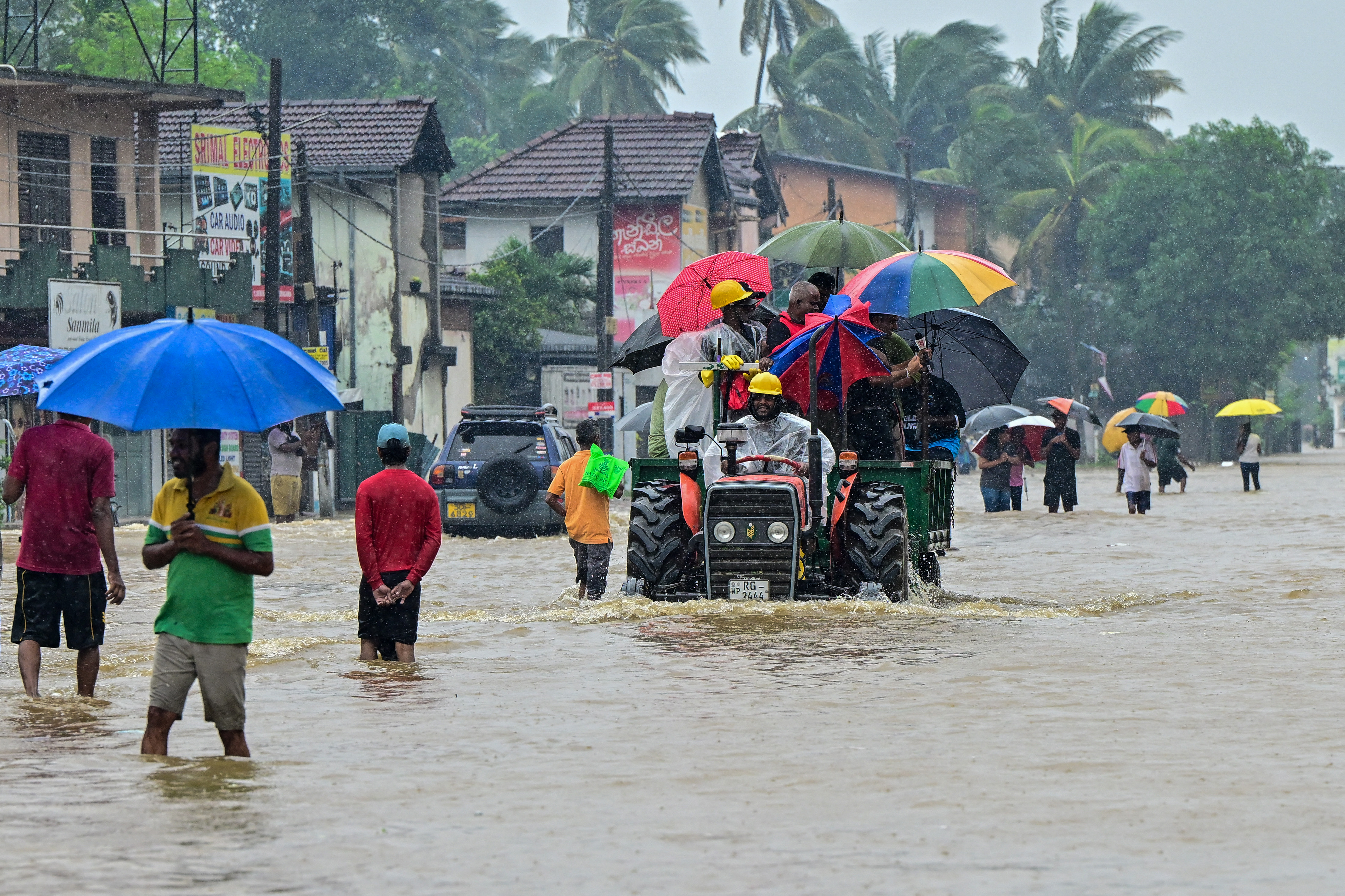 People move through a flooded road after heavy rainfall in Kaduwela on the outskirts of Colombo on November 28, 2025.