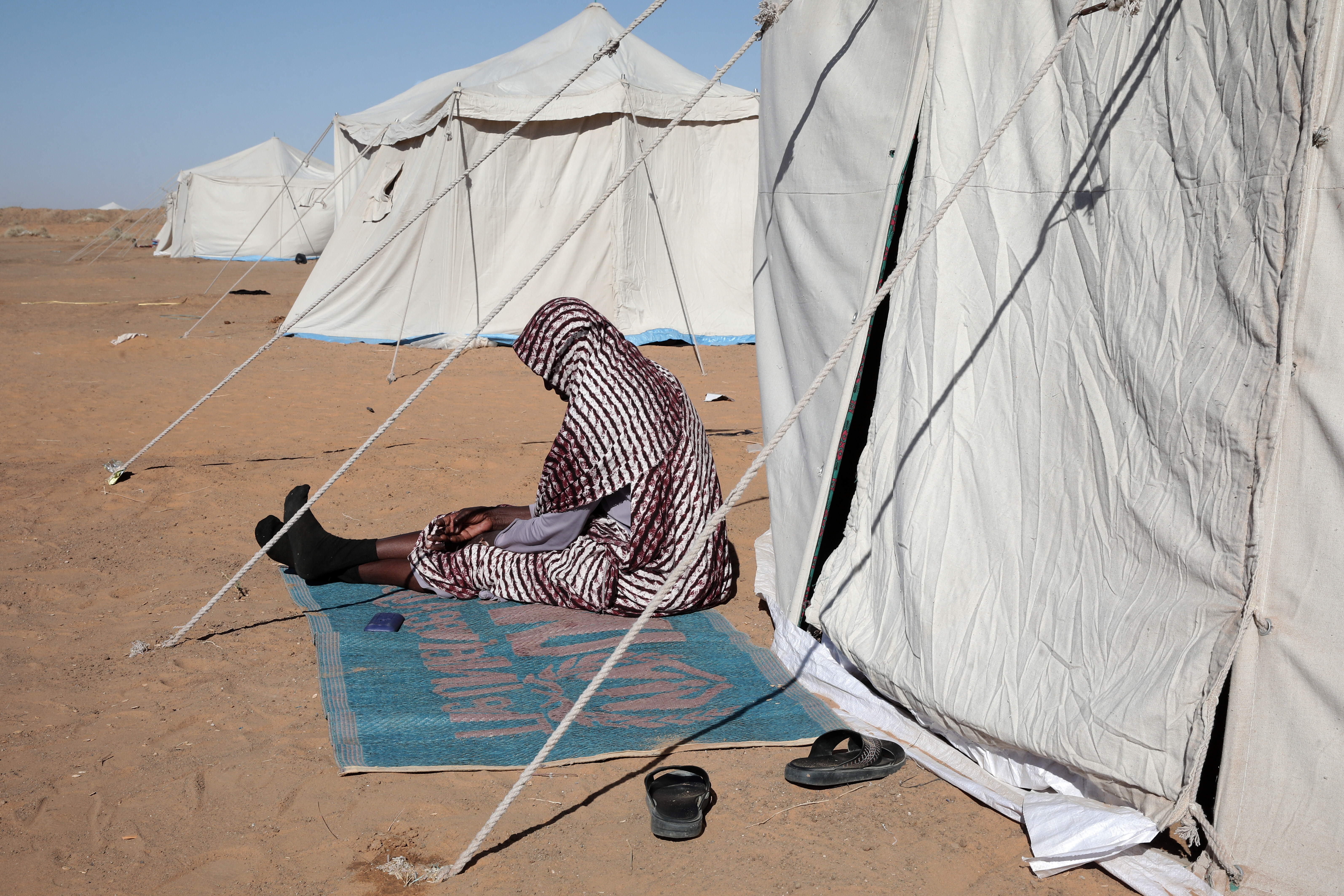 A Sudanese woman displaced from El-Fasher sits outside his tent at the newly established El-Afadh camp in Al Dabbah, in Sudan's Northern State, Sunday, Nov. 16, 2025. (AP Photo/Marwan Ali)