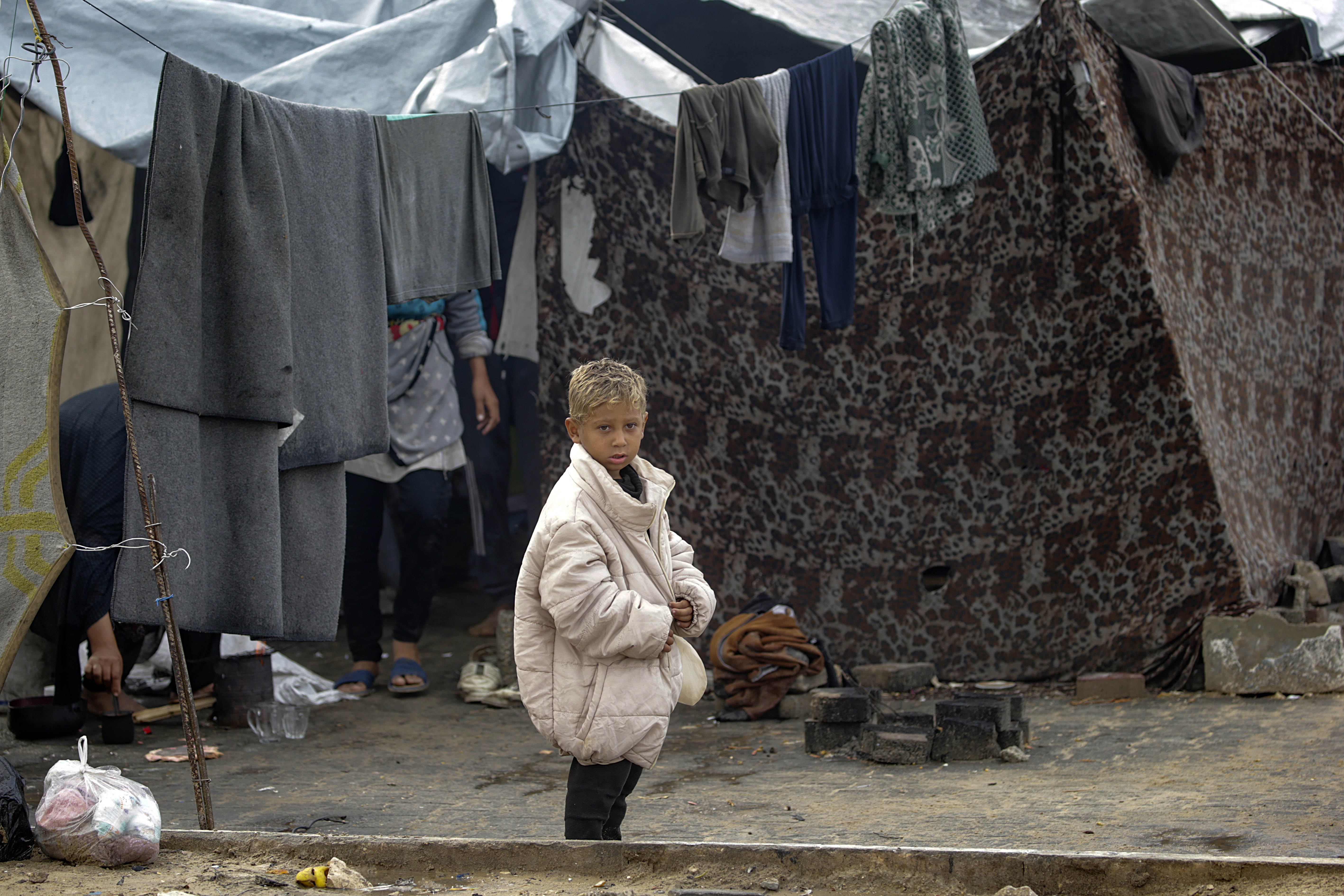 epa12525509 A displaced Palestinian child stands outside his family's shelter during a rainy day at a makeshift camp, west of Gaza City, Gaza Strip, 14 November 2025. Around 1.9 million people in Gaza, nearly 90 percent of the population, have been displaced since the Israel-Hamas conflict began in October 2023, according to the UN. EPA/MOHAMMED SABER