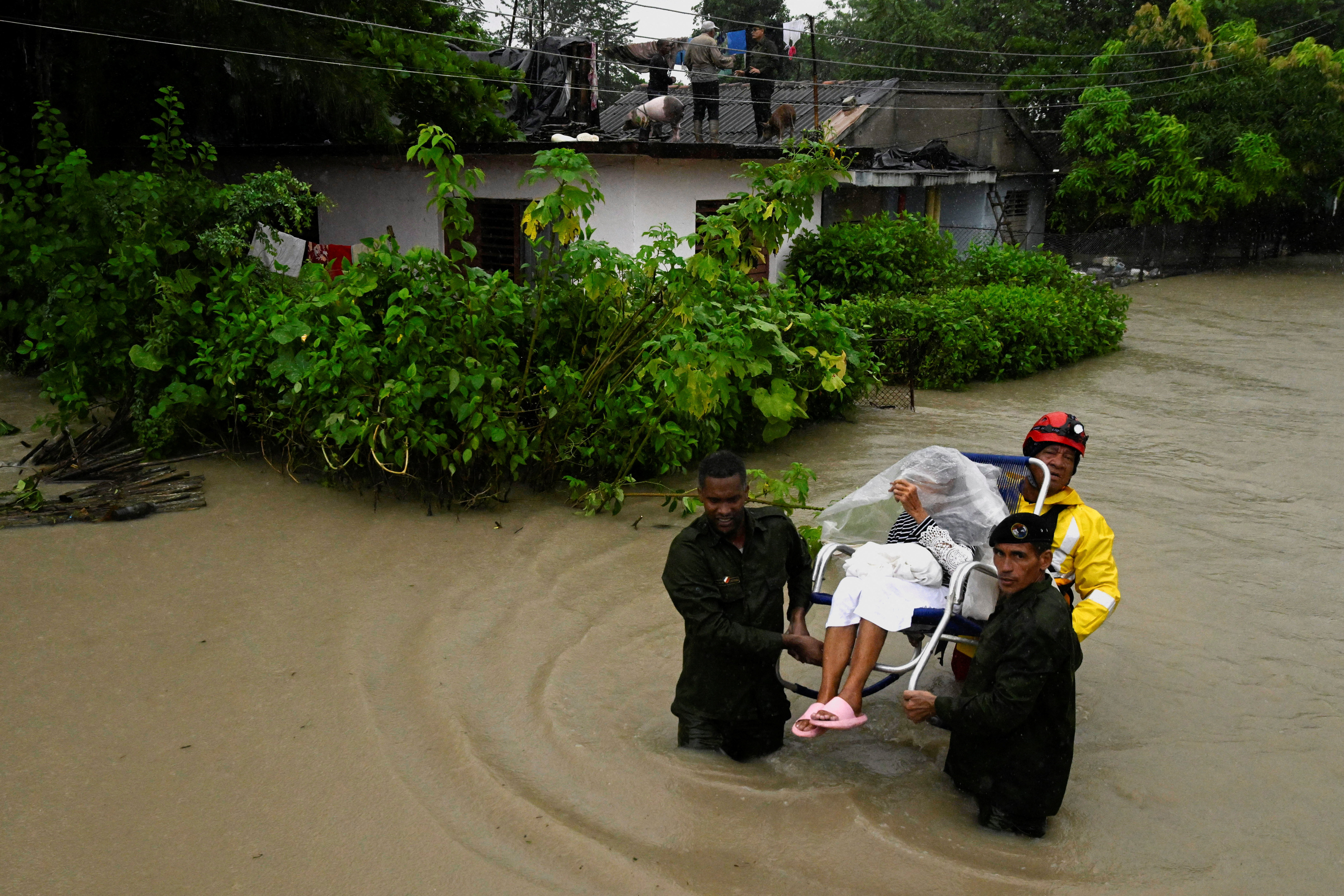 A woman is evacuated from her home by emergency personnel after the Cauto River flooded due to Hurricane Melissa, in Rio Cauto, Granma Province, Cuba October 31, 2025. REUTERS/Norlys Perez