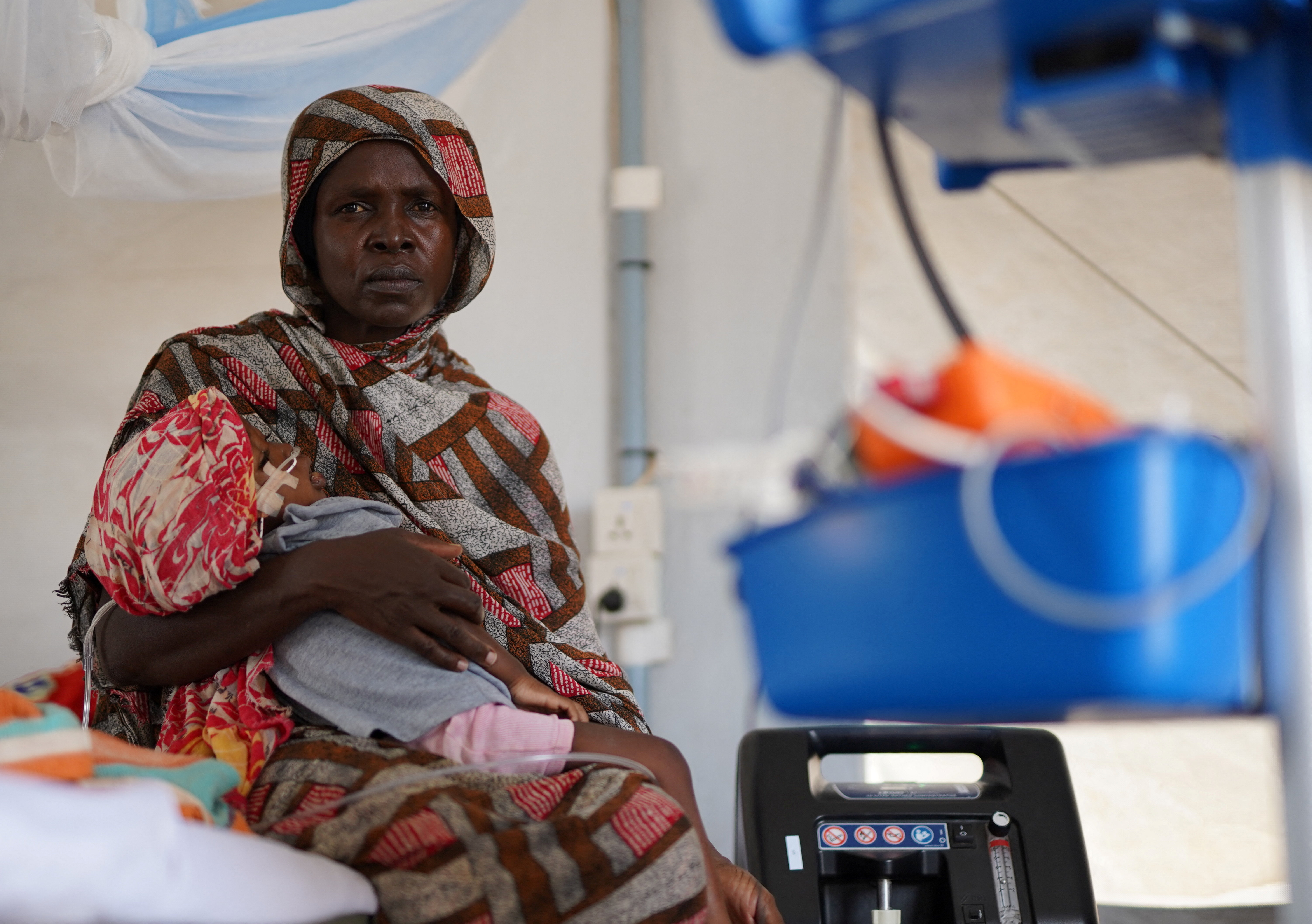 An injured displaced Sudanese woman who fled violence in al-Fashir receives treatment while carrying her child at a makeshift clinic run by Medecins Sans Frontieres (MSF), amid ongoing clashes between the paramilitary Rapid Support Forces (RSF) and the Sudanese army, in Tawila, North Darfur, Sudan November 3, 2025. REUTERS/Mohamed Jamal
