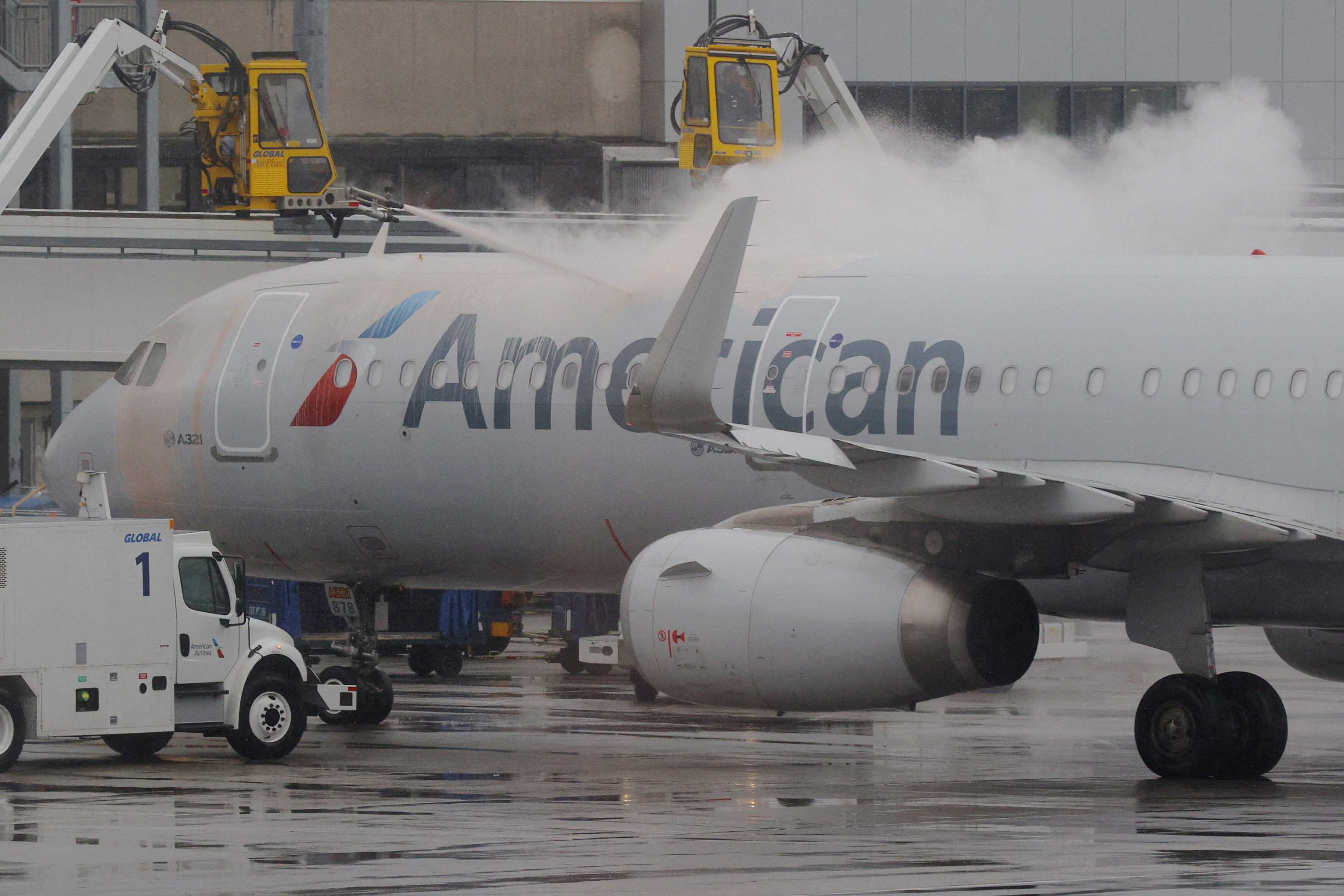Crews spray de-icer on an American Airlines plane during a winter storm at Logan Airport in Boston, Massachusetts, U.S., February 28, 2023. REUTERS/Brian Snyder