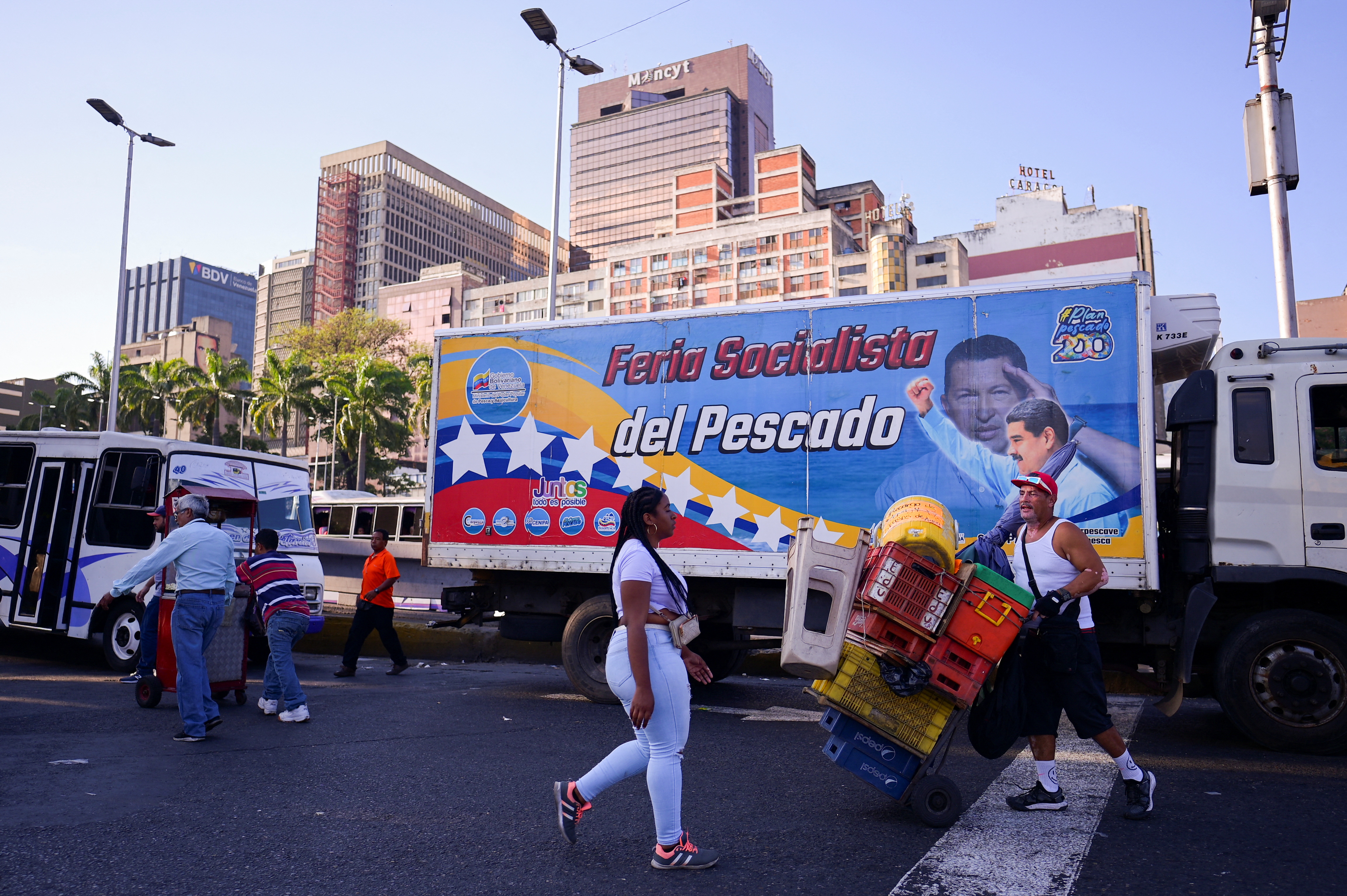 People walk past a bus with pictures of Venezuelan President Nicolas Maduro and Venezuela's late President Hugo Chavez