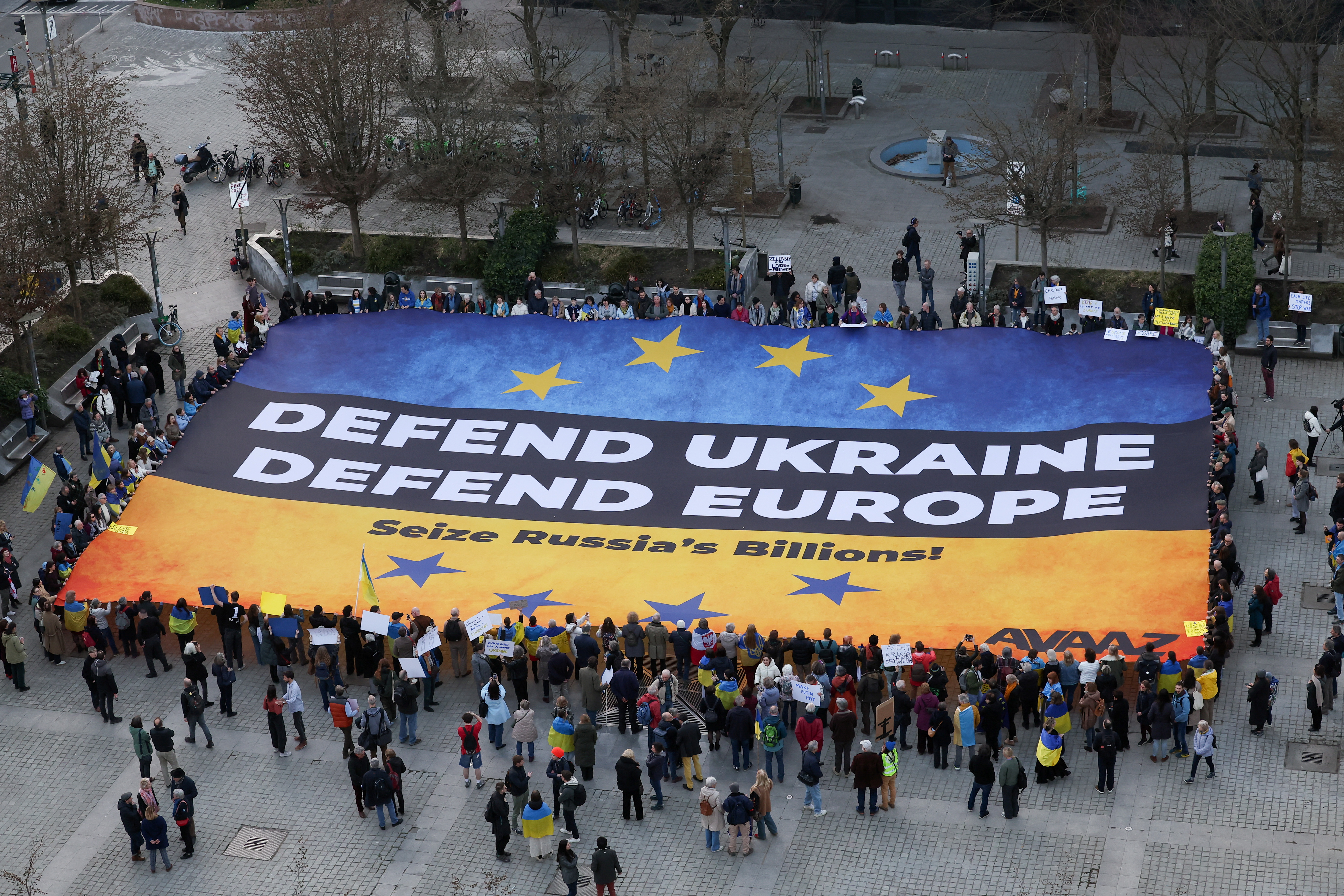Ukrainian activists deploy a massive banner, urging European leaders to seize frozen Russian assets to fund Ukraine in its conflict against Russia, in Brussels Belgium, March 5, 2025. REUTERS/Yves Herman