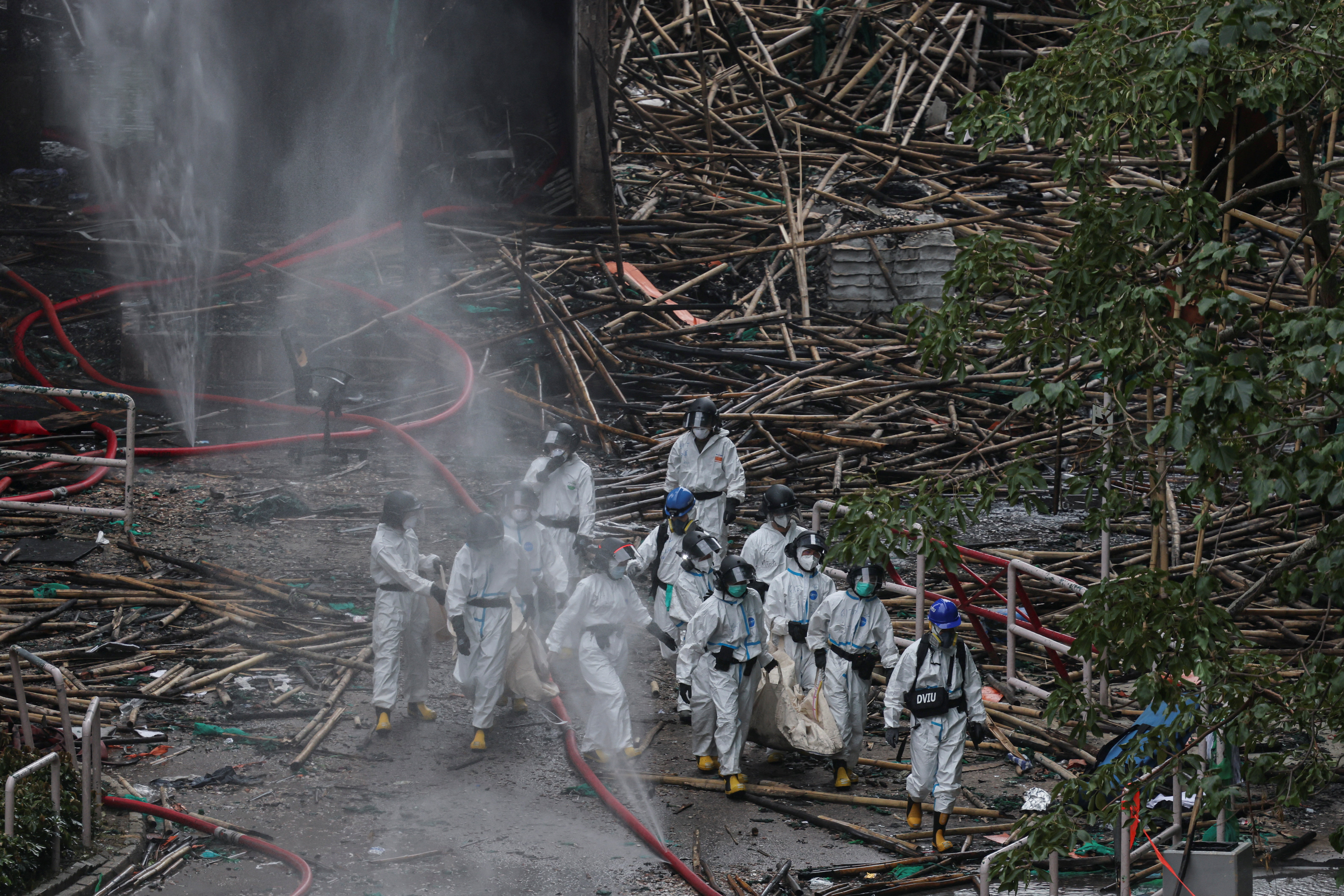 Police officers carry a body recovered from a fire-damaged residential block.