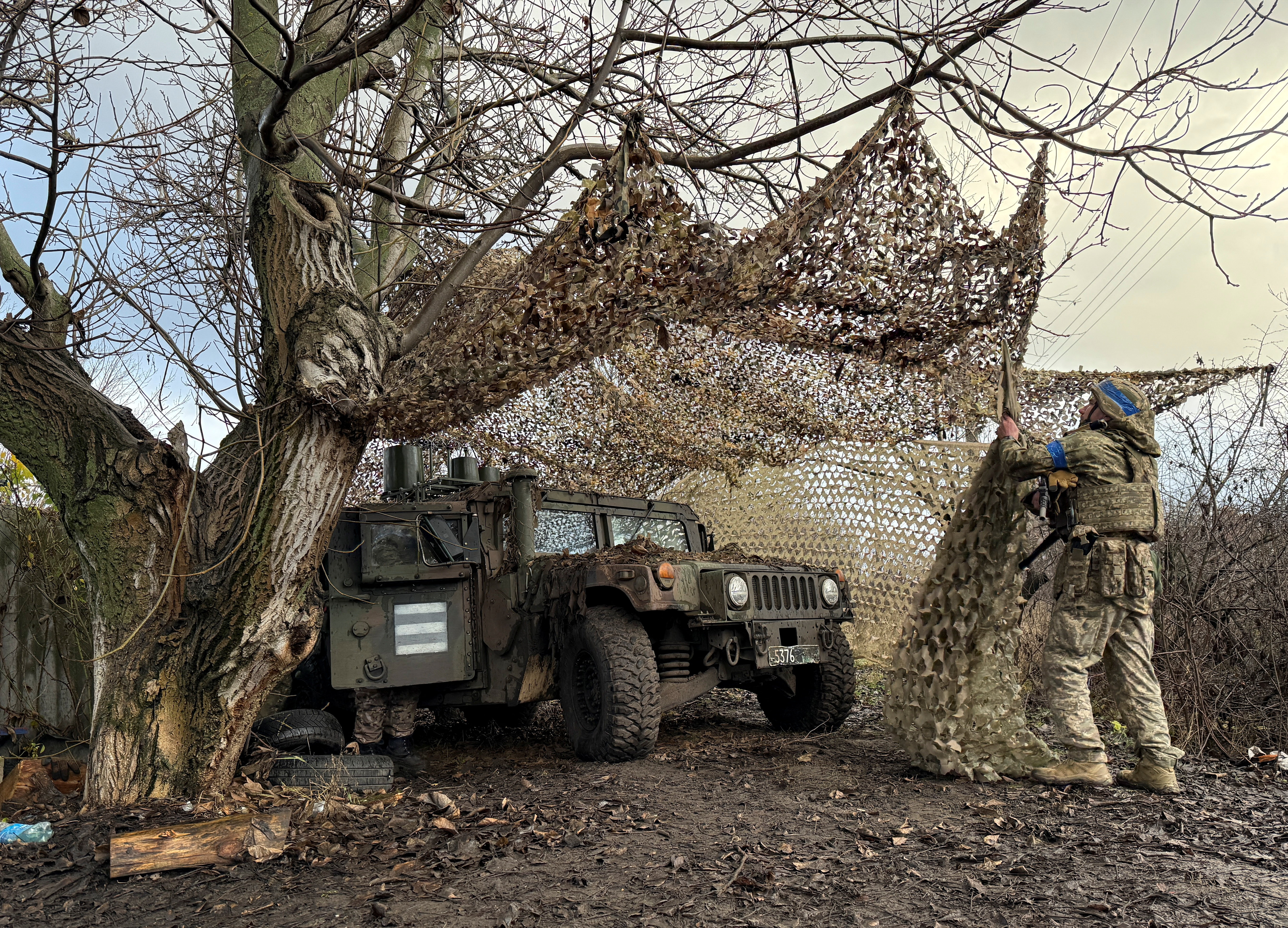 Ukrainian serviceman camouflages an HMMWV (Humvee) vehicle, amid Russia's attack on Ukraine, near the frontline town of Kupiansk, Ukraine December 12, 2025. REUTERS/Stringer