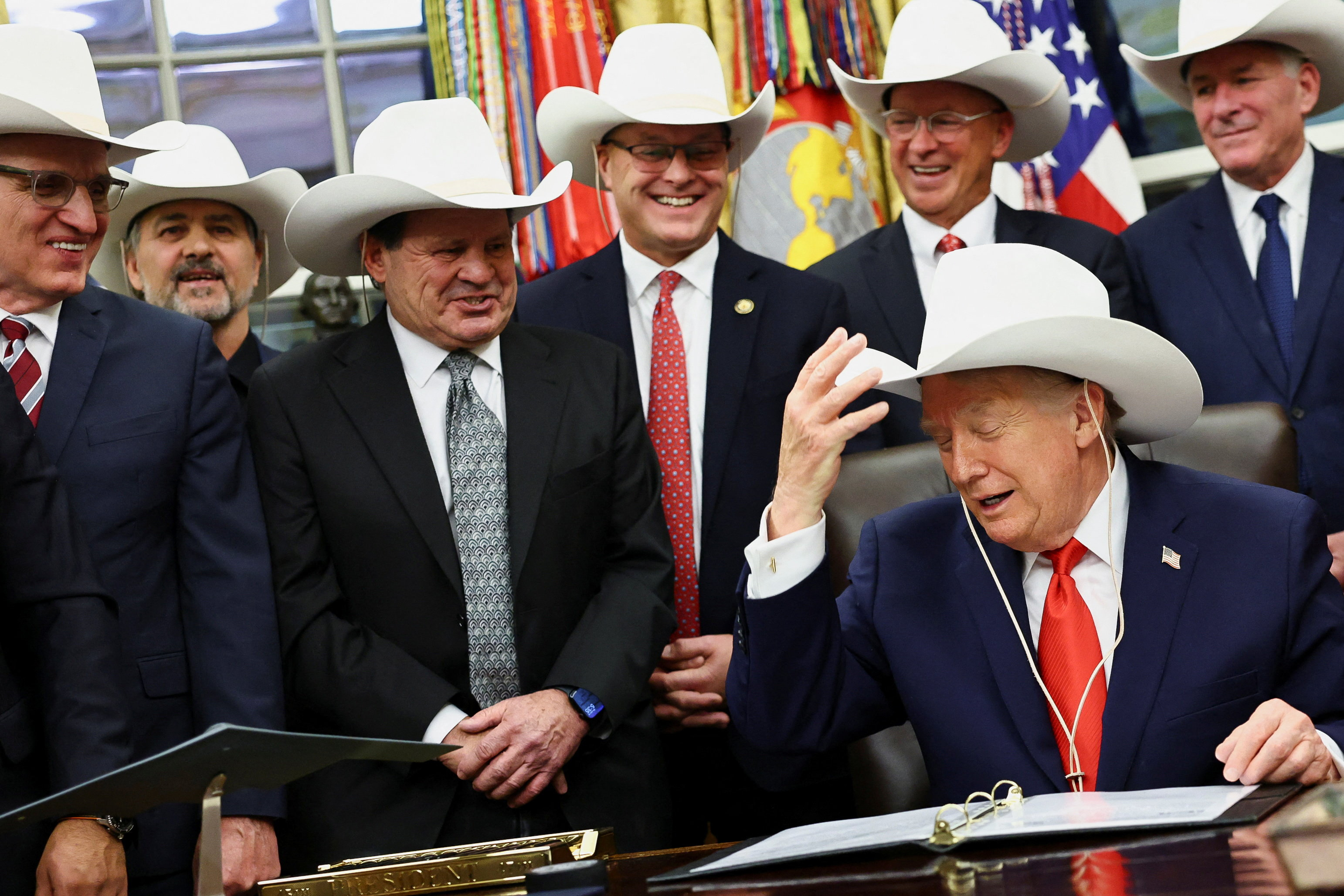 Trump tries on a cowboy hat with members of the 1980 US hockey team