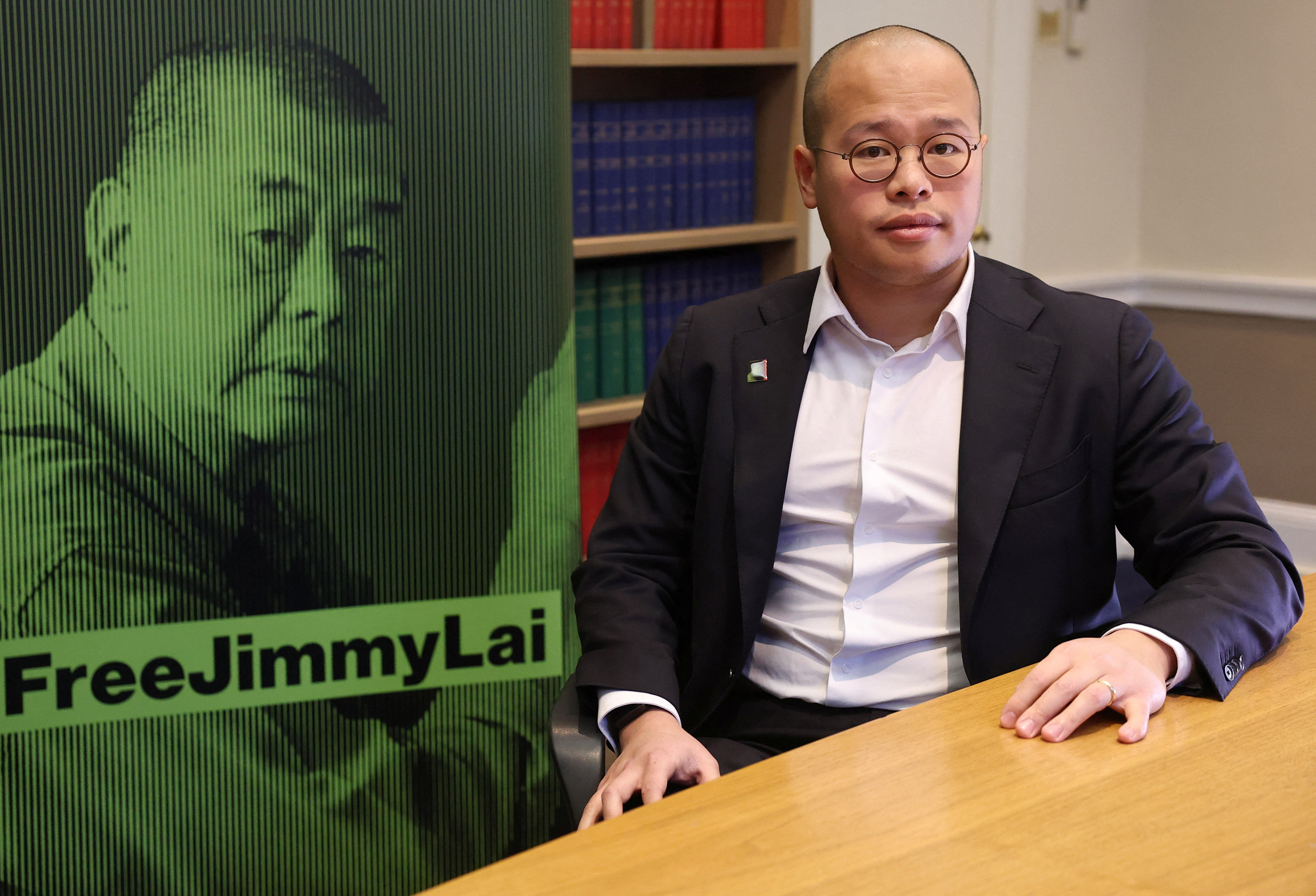 Sebastien Lai, son of jailed media tycoon Jimmy Lai, poses for a portrait next to a campaign poster featuring imagery of his father, during an interview with Reuters following his father being found guilty under Hong Kong’s national security law of conspiracy to collude with foreign forces and to publish seditious material, in London, Britain, December 15, 2025. REUTERS/Toby Melville
