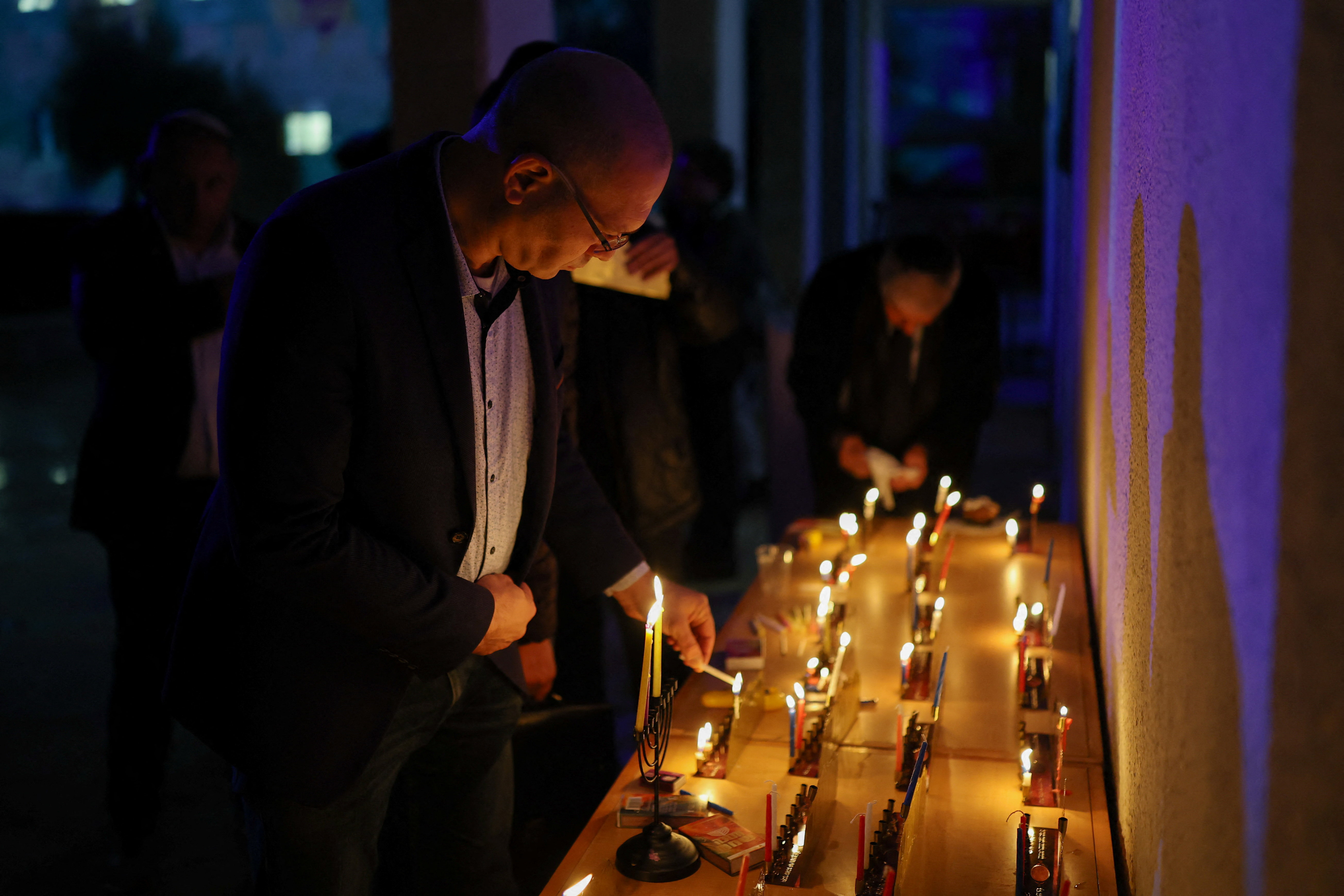 A man lights a candle of a Hanukkah during a vigil, following a fatal shooting at Sydney's Bondi Beach during celebrations for the Jewish holiday of Hanukkah, in Jerusalem