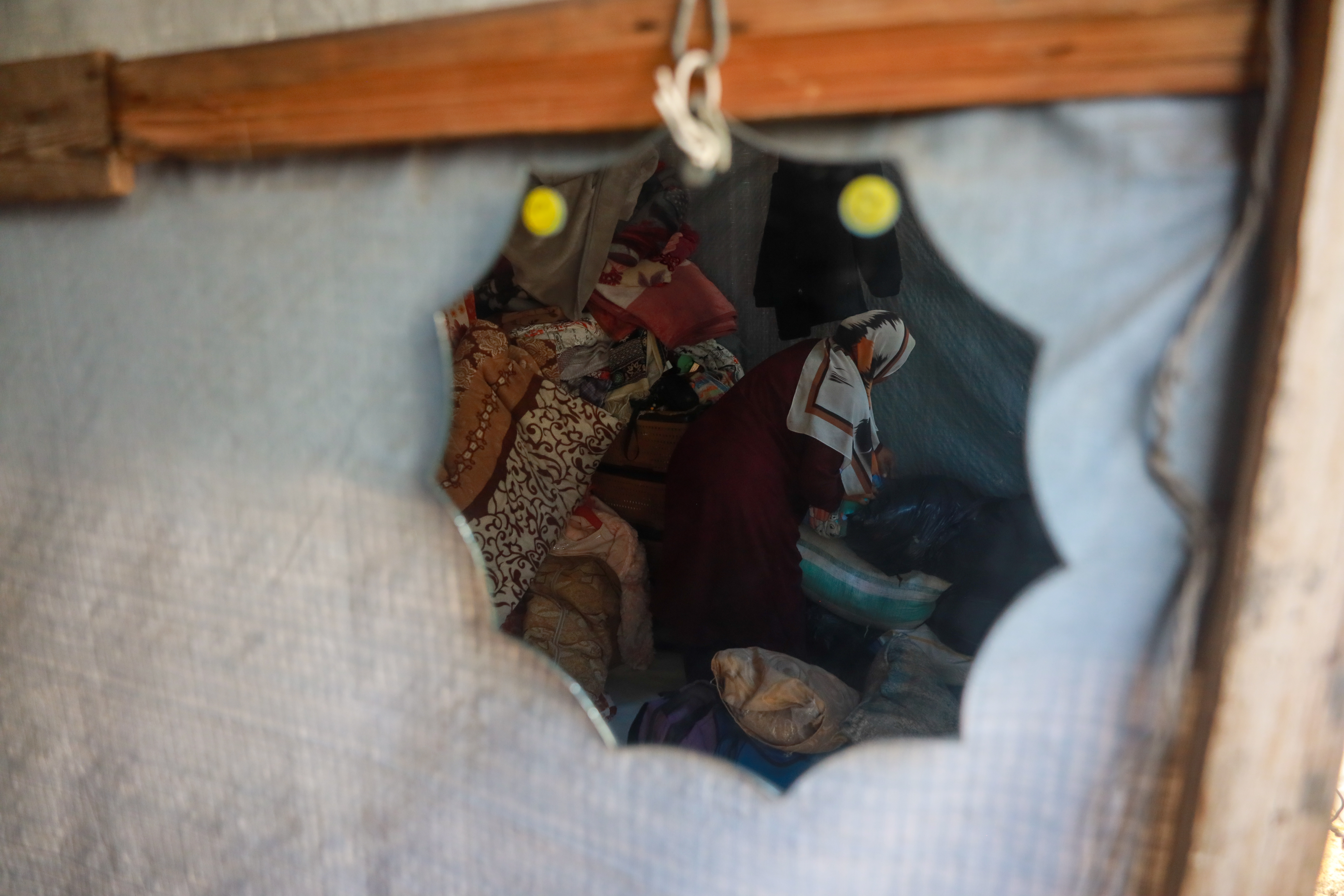A woman cleaning in a tent, reflected through a mirror
