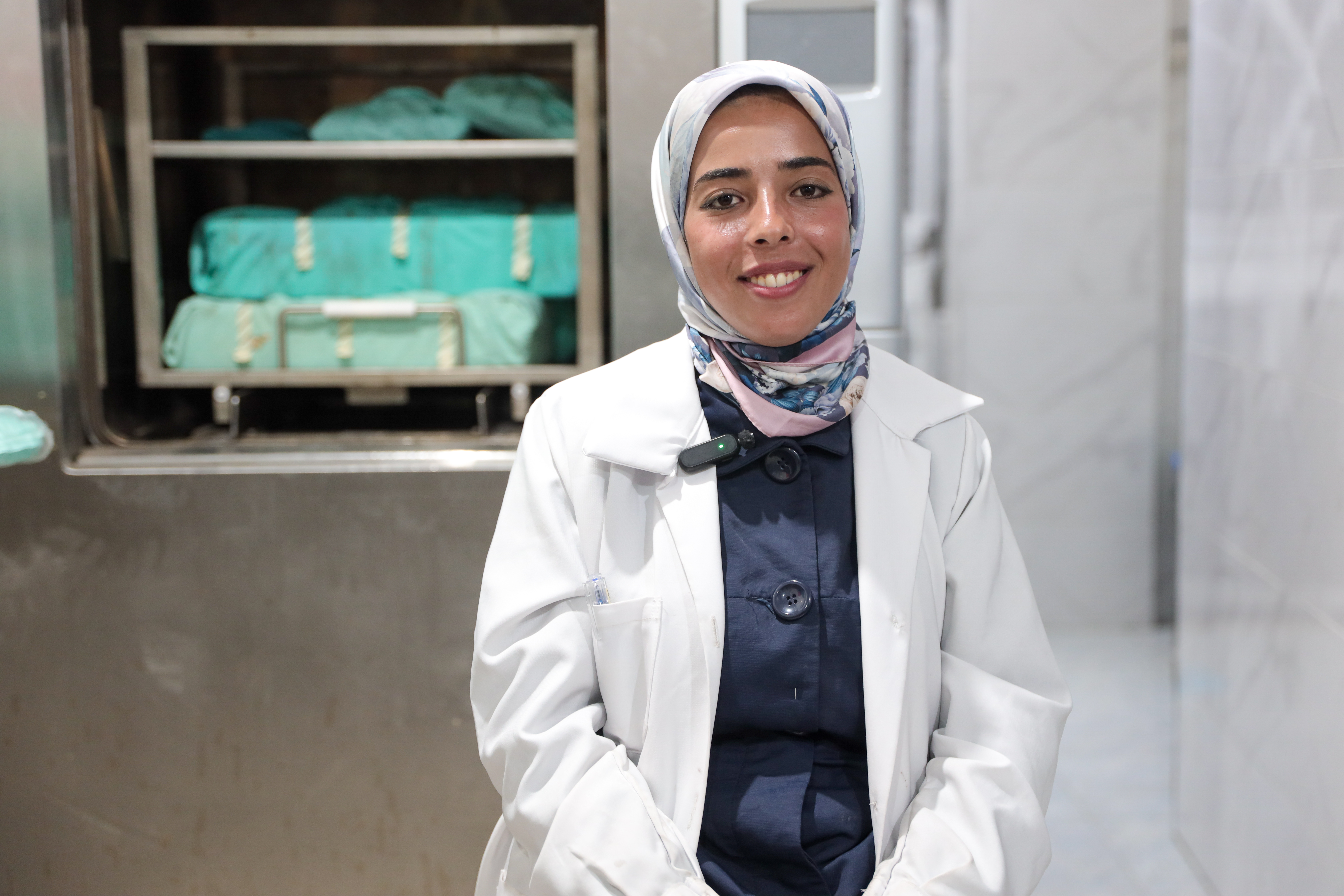 Doctor in her white coat and a hijab smiles at the camera