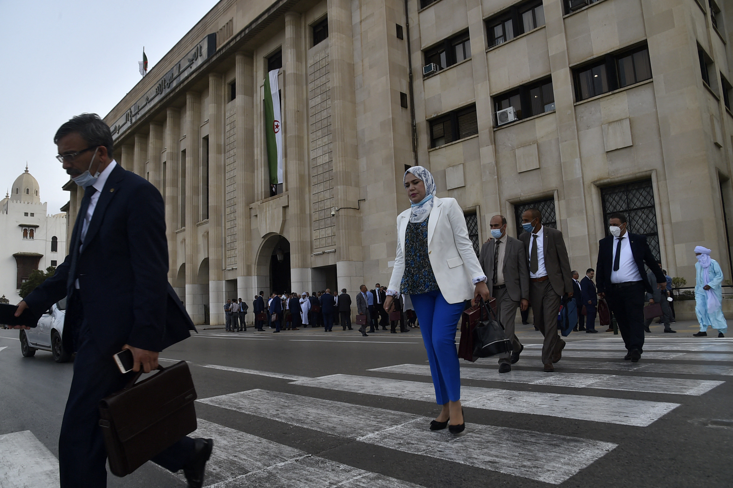 Algerian politicians walk outside the People's National Assembly in Algiers