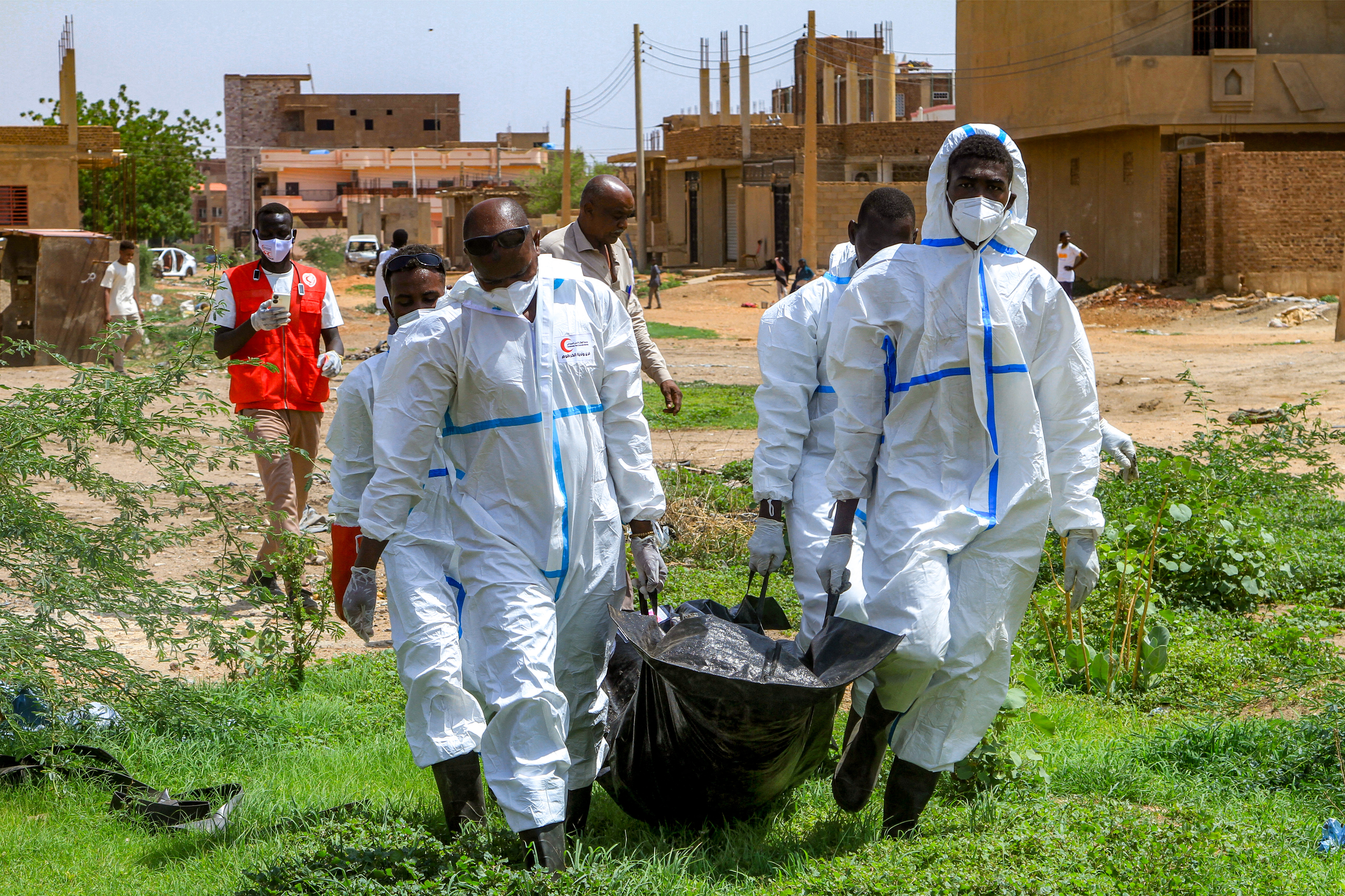 Members of the Sudanese Red Crescent carry in a bag the exhumed remains of a person from a makeshift grave for reburial in the local cemetery in Khartoum's southern suburb of al-Azhari
