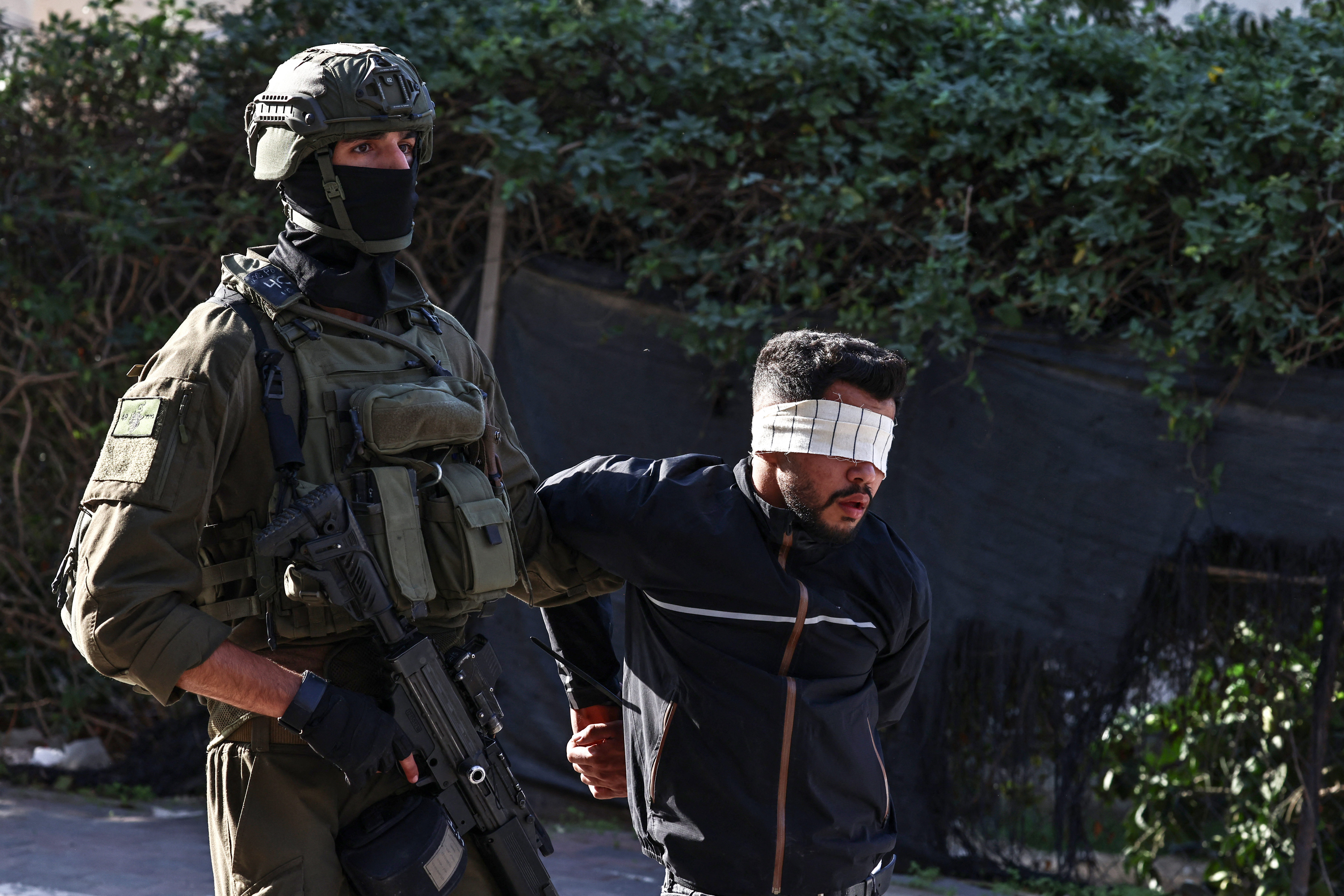 An Israeli soldier arrests a Palestinian man.