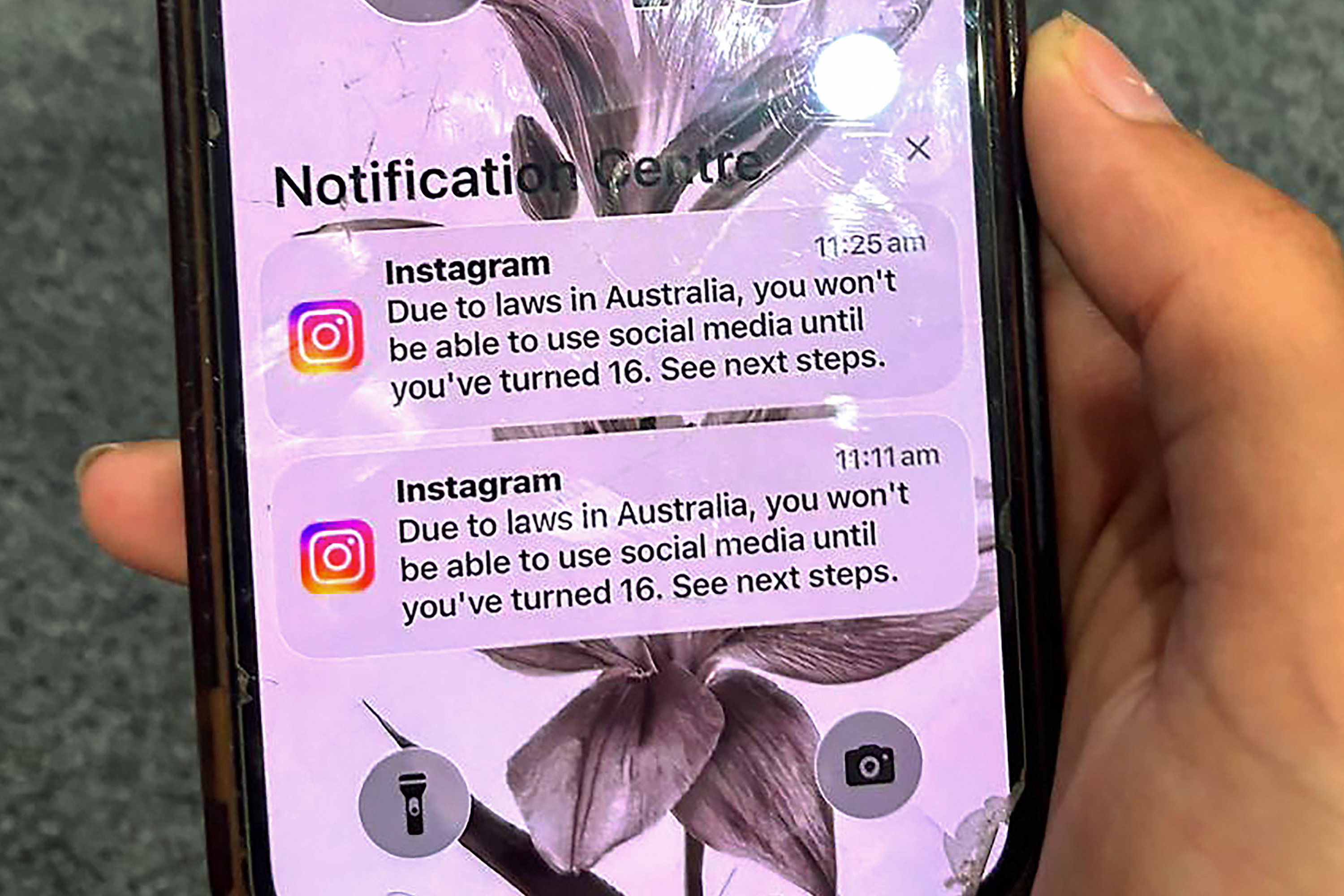 A teenager holds a mobile phone displaying a message from social media platform Instagram after the account was locked for age verification in Sydney, Australia on December 9, 2025.