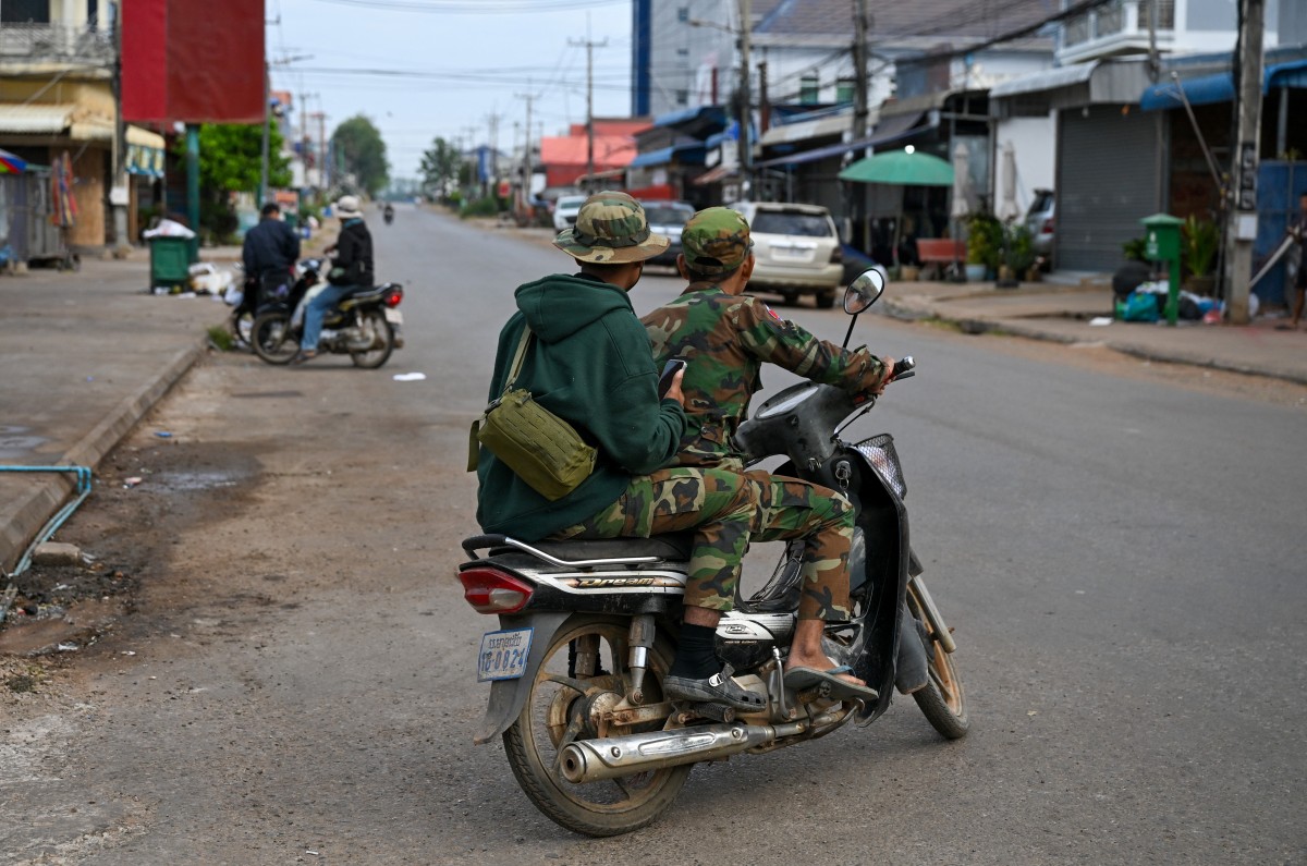 Soldiers ride a motorcycle along a street in Oddar Meanchey province on December 10, 2025 following clashes along the Cambodia-Thailand border.Fighting between Thailand and Cambodia spread to more parts of their contested border on Tuesday, forcing a mass exodus of civilians as the renewed hostilities derailed a US-brokered truce.