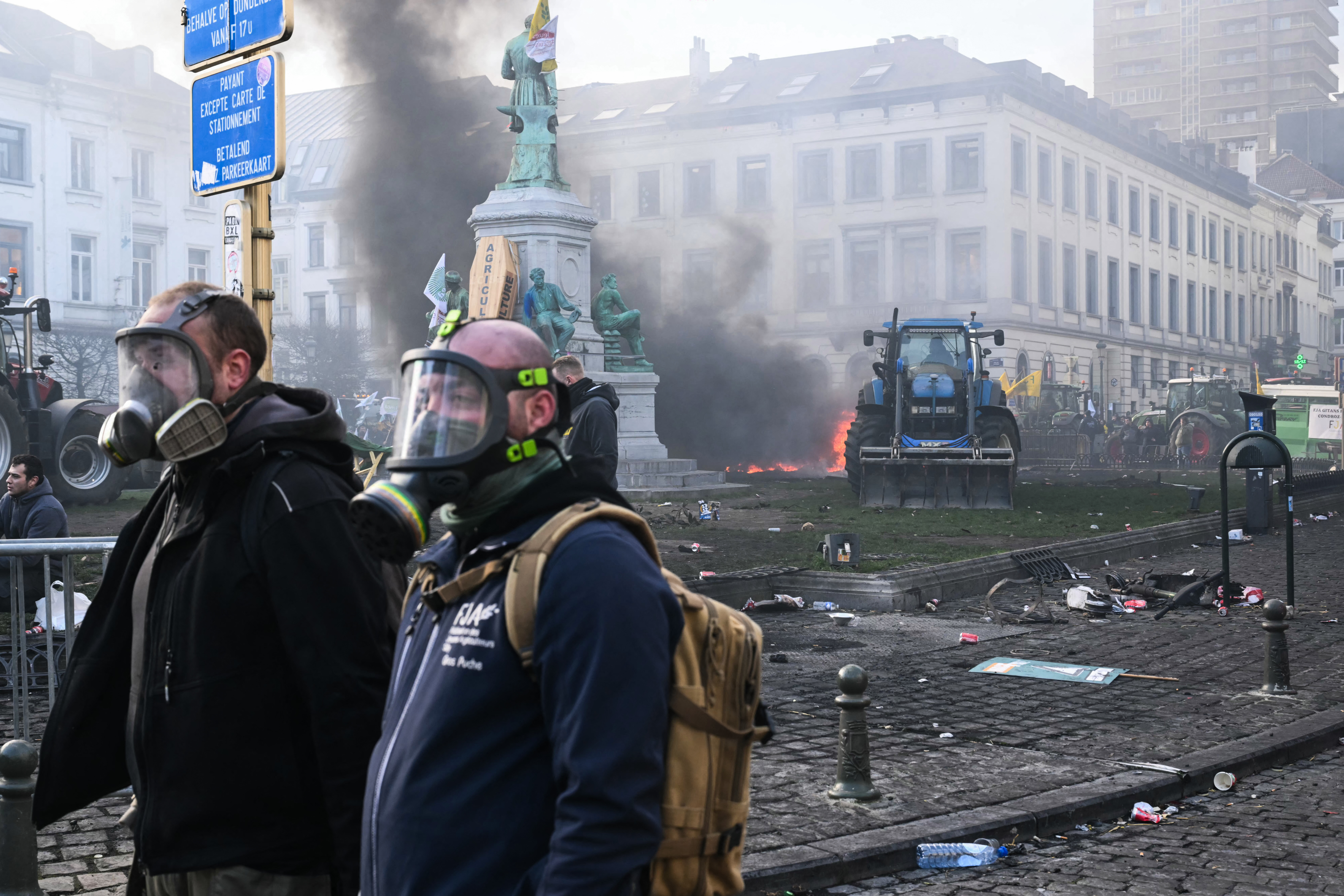 Farmers wear gas masks at the Place du Luxembourg near the European Parliament, during a farmers' protest to denounce the reforms of the Common Agricultural Policy (CAP) and trade agreements such as the Mercosur, in Brussels, on December 18, 2025, organised by Copa-Cogeca, the main association representing farmers and agricultural cooperatives in the EU. EU Farmers, particularly in France, worry the Mercosur deal -- which will be discussed at the EU leaders meeting -- will see them undercut by a flow of cheaper goods from agricultural giant Brazil and its neighbours. They also oppose plans put forward by the European Commission to overhaul the 27-nation bloc's huge farming subsidies, fearing less money will flow their way. (Photo by NICOLAS TUCAT / AFP)