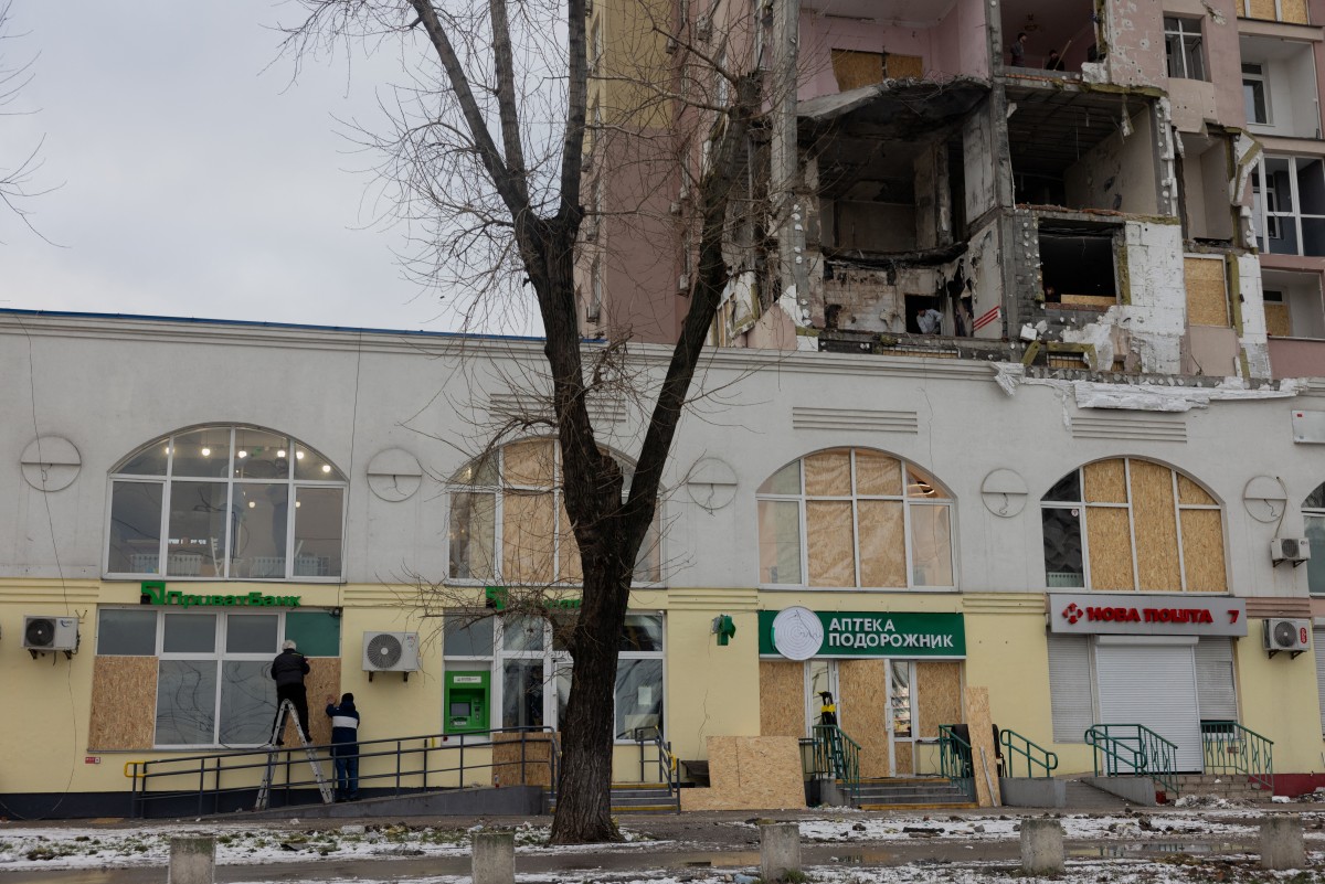Men cover damaged windows with plywood in a damaged residential building following Russian drones and missiles attack, in Kyiv, on December 28, 2025, amid the Russian invasion in Ukraine. A Russian drone and missile barrage on Kyiv and its suburbs killed one person, wounded two dozen and cut off heating and electricity for hundreds of thousands of people left in freezing temperatures on December 27, 2025.