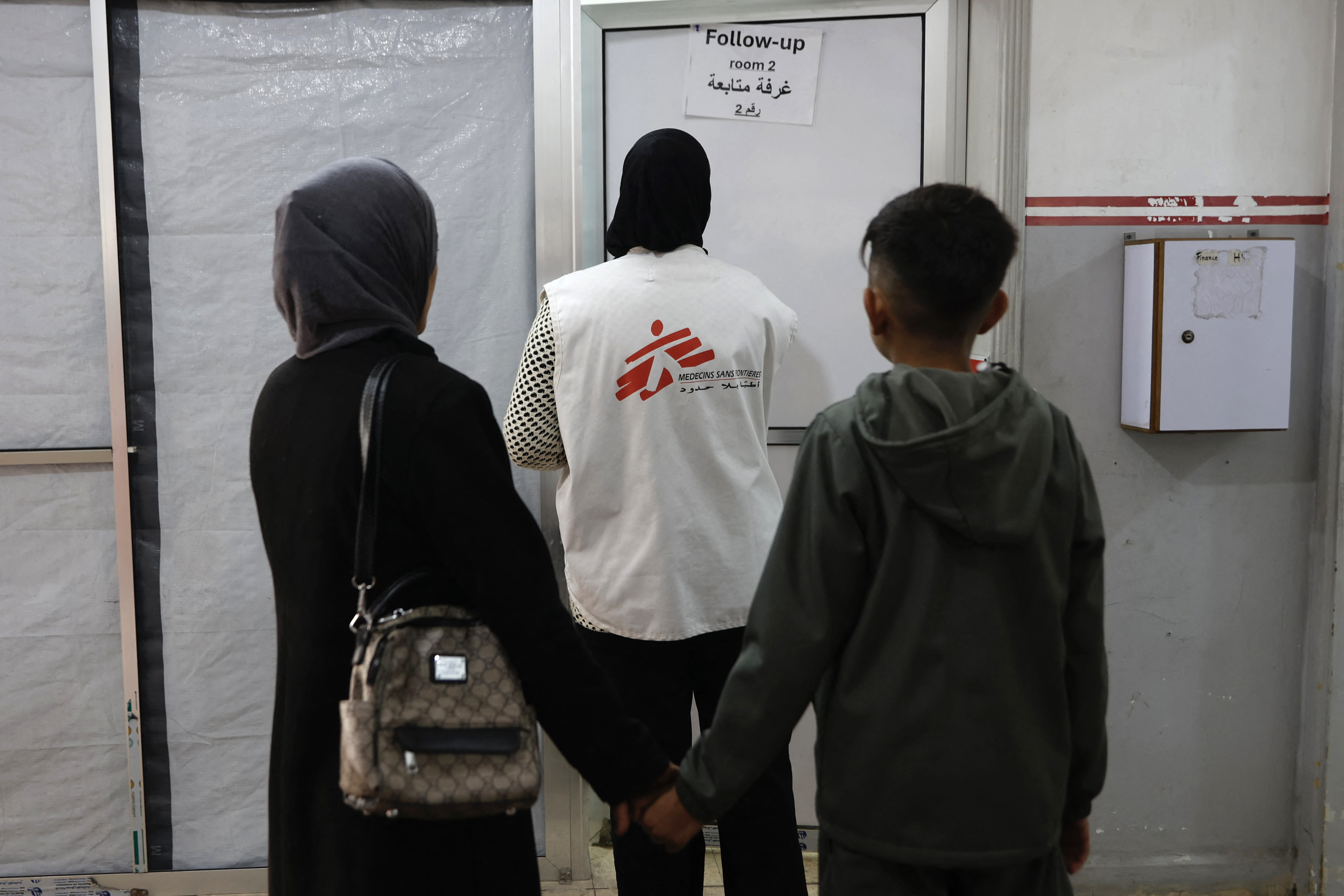Patients follow a member of staff at the Doctors Without Borders or Medecins Sans Frontieres (MSF) to the follow up room at a clinic, in the al-Rimal neighborhood of Gaza City on new year's Eve, December 31, 2025. [Omar Al-Qattaa/ AFP]