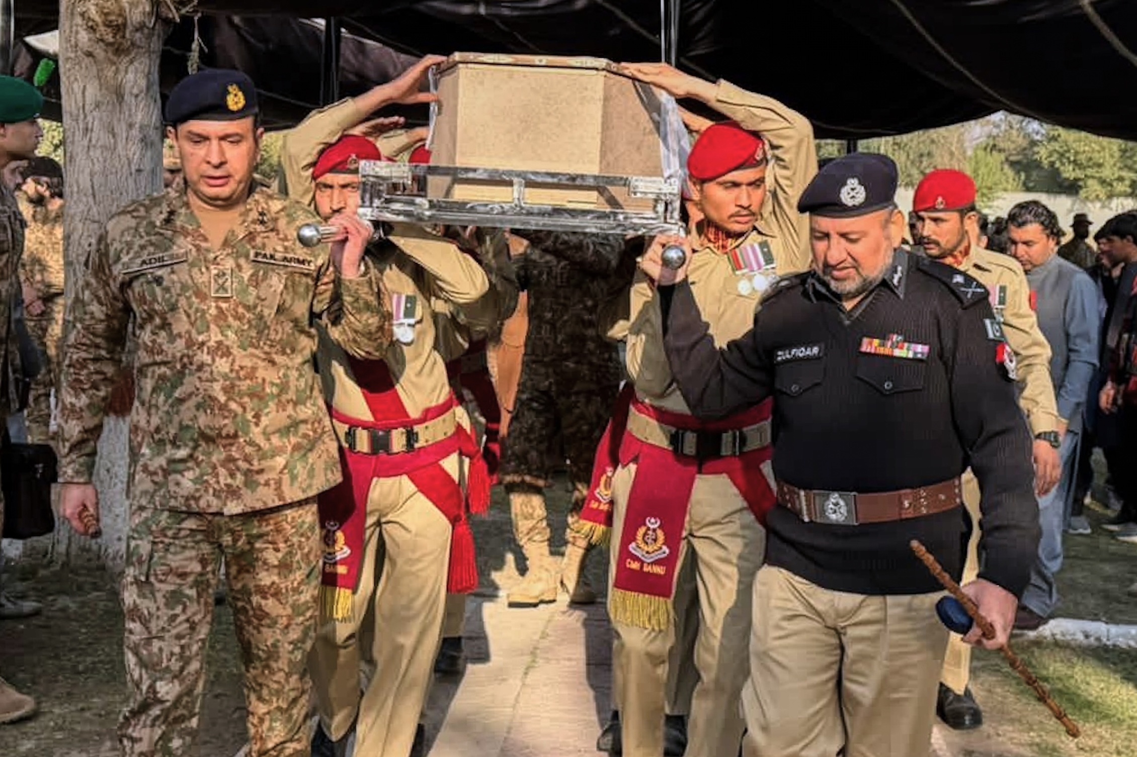 Army troops and a police officer carry the casket of a government administrator killed in an attack on Tuesday in Bannu, Pakistan