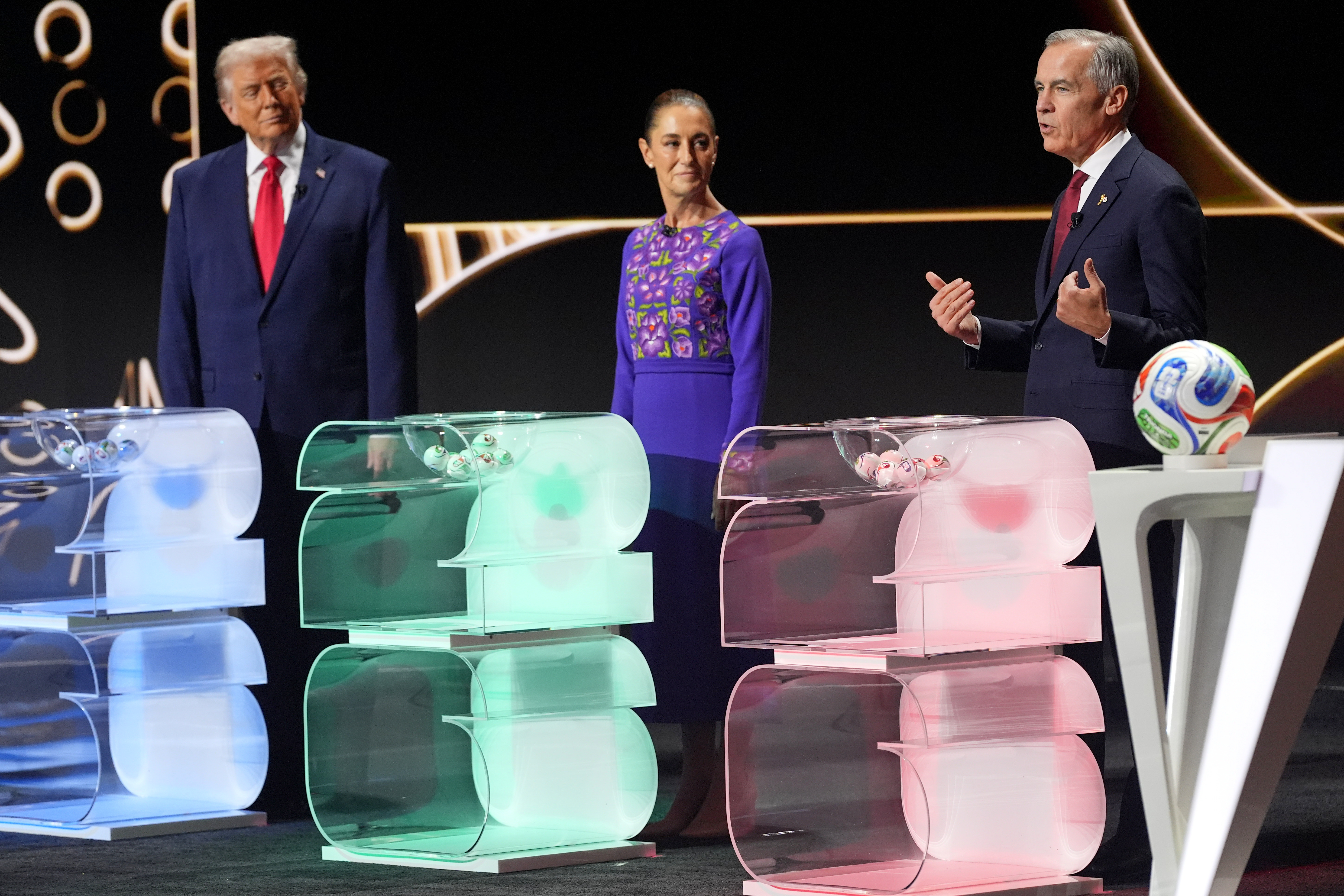 Canadian Prime Minister Mark Carney, right, speaks as he stands on stage with Mexican President Claudia Sheinbaum and President Donald Trump during the draw for the 2026 soccer World Cup at the Kennedy Center in Washington, Friday, Dec. 5, 2025. (AP Photo/Jacquelyn Martin)