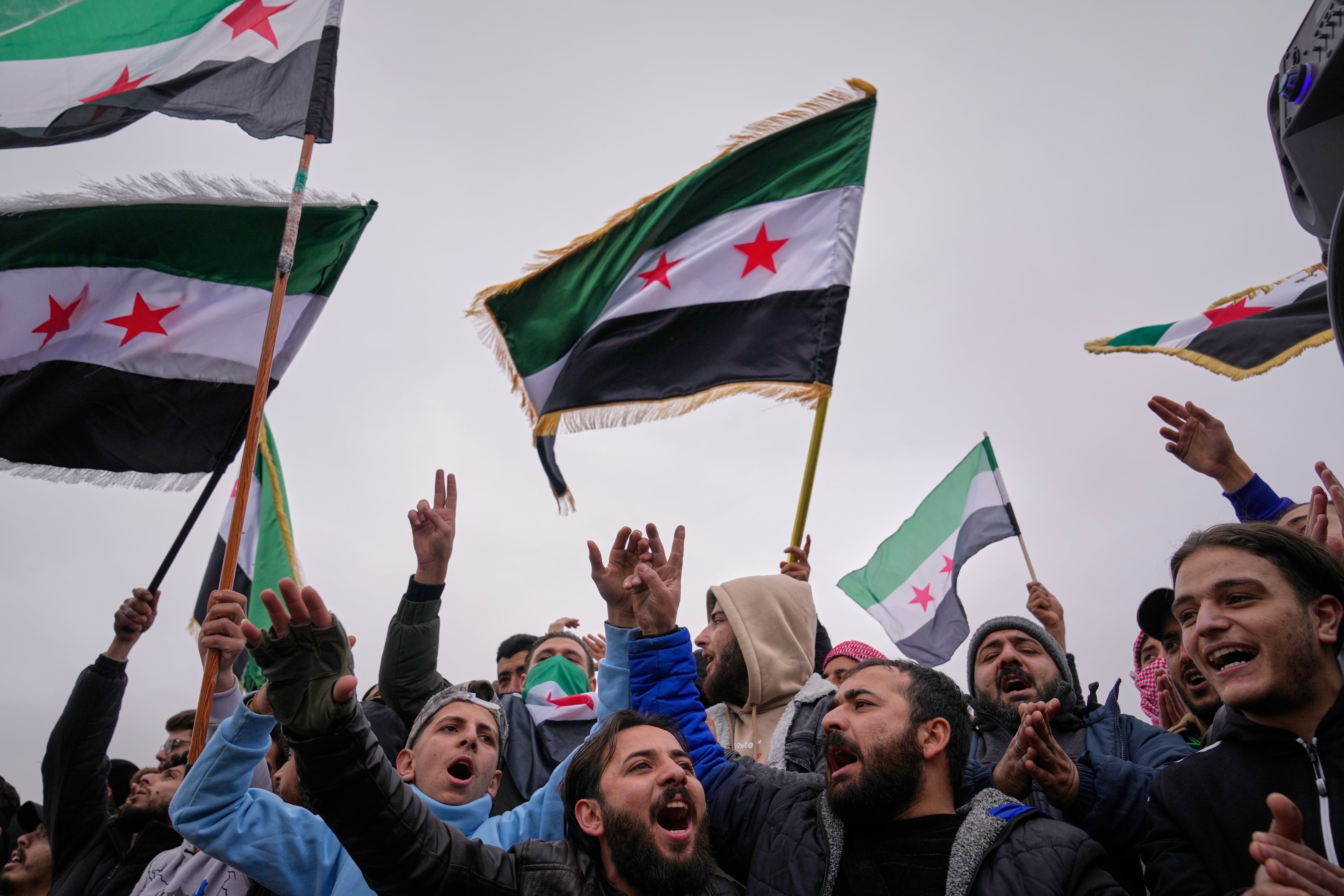 People celebrate and wave Syrian flags.