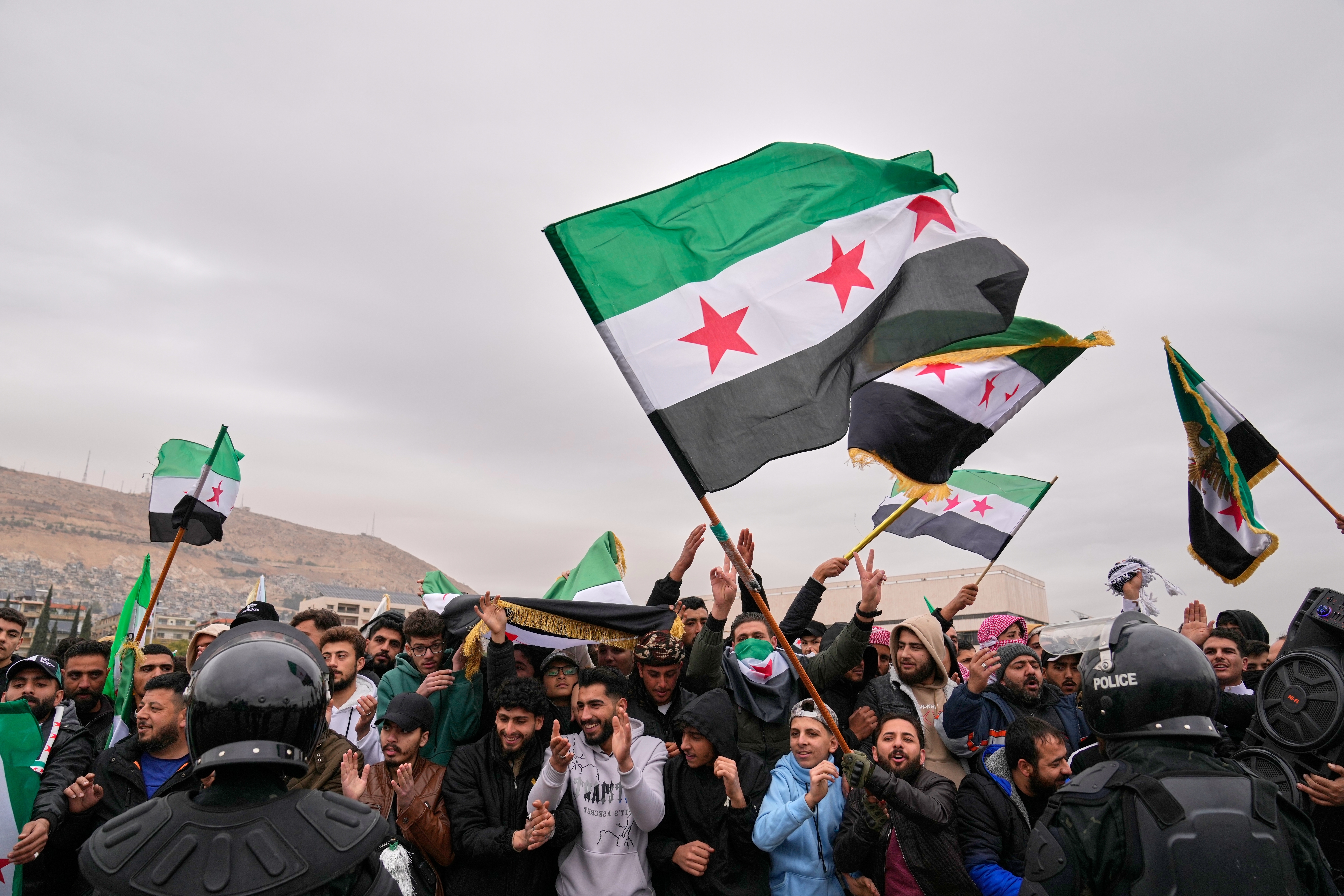 People celebrate and wave Syrian flags.