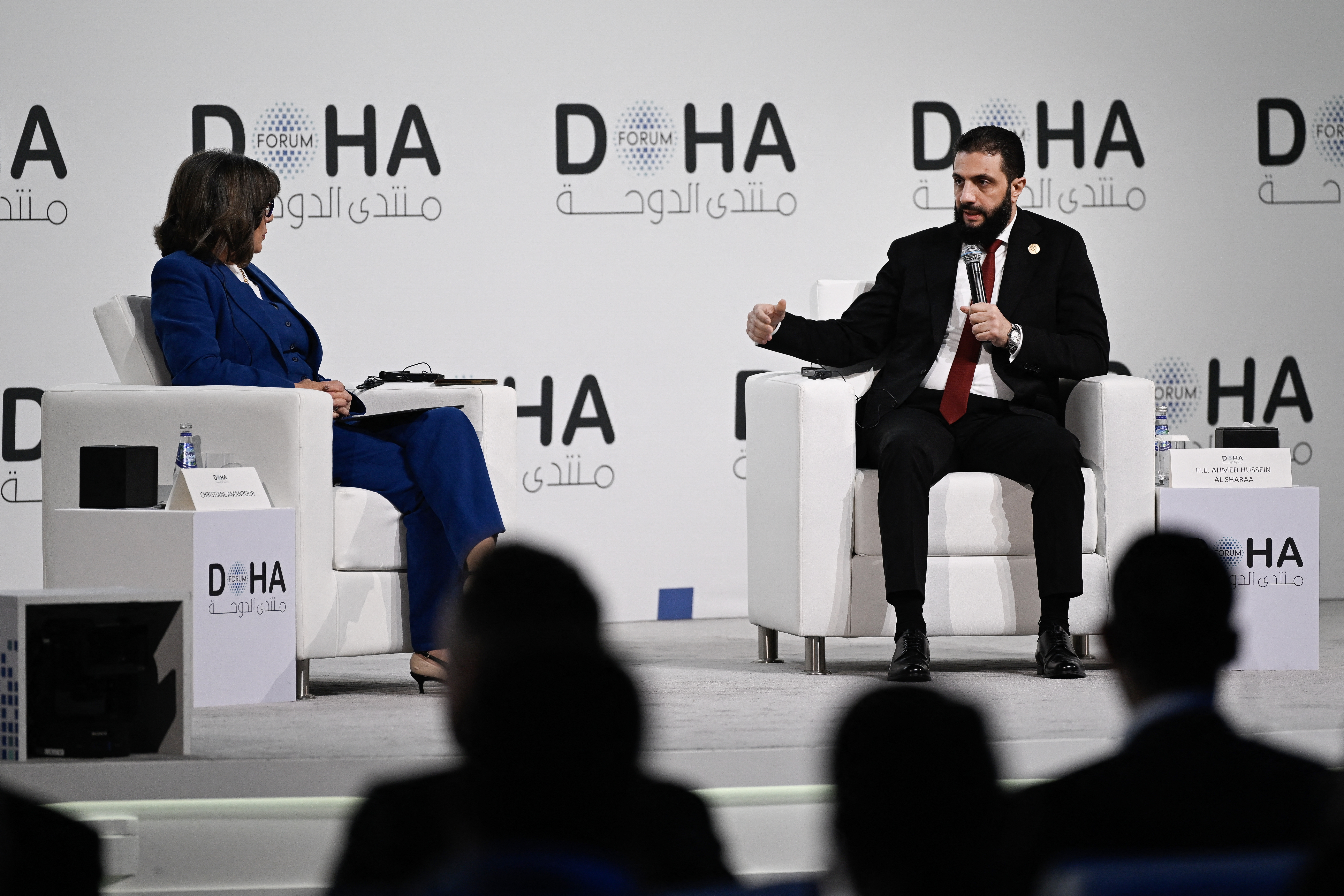 Syrian President Ahmed al-Sharaa (R) speaks during the opening day of the Doha Forum, an annual diplomatic conference, in Doha on December 6, 2025.