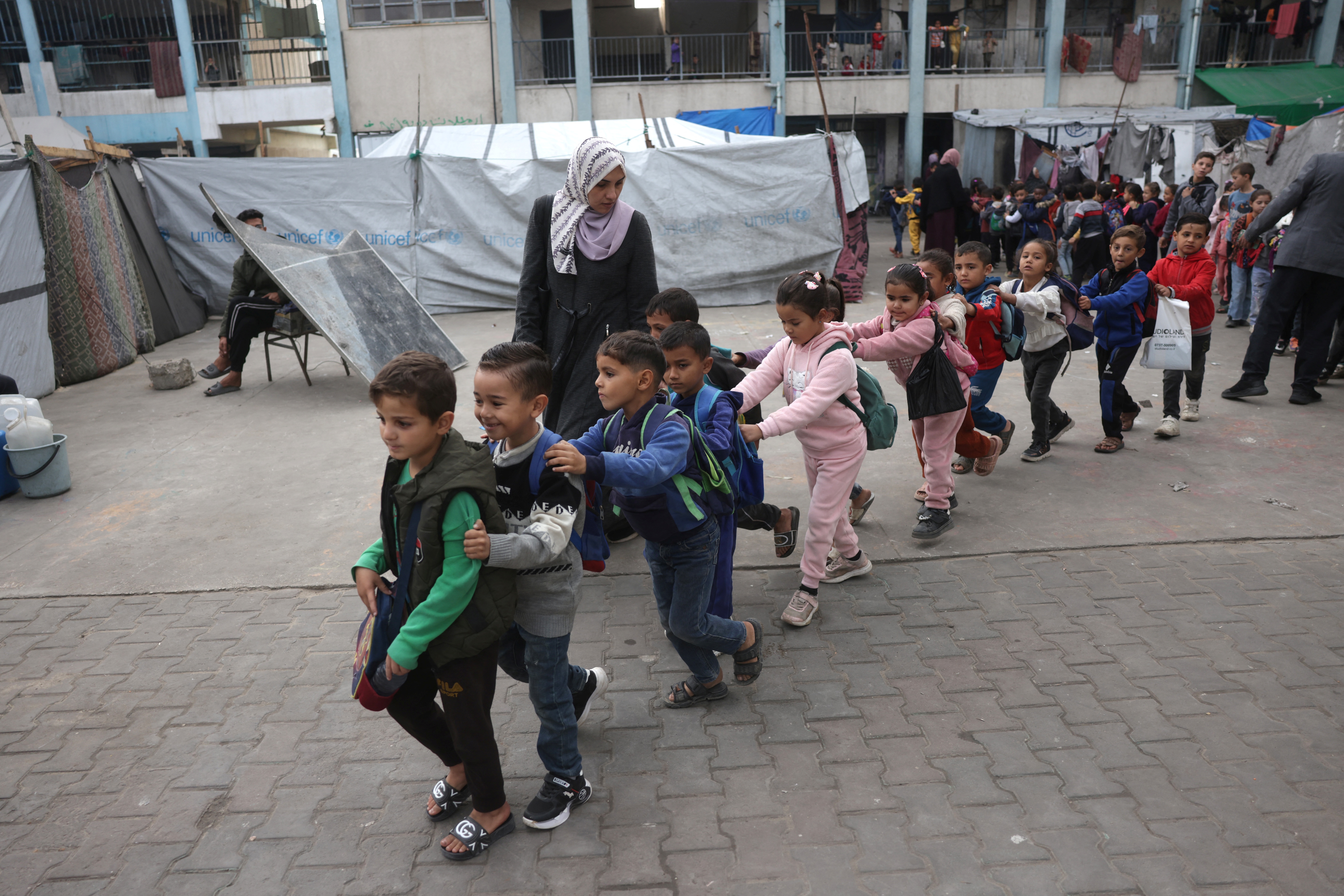 Palestinian children, many of whom are part of displaced families, gather in the yard of the UNRWA Deir al-Balah Joint School, west of Deir al-Balah, in the central Gaza Strip on December 6, 2025, under the first phase of the fragile US-brokered ceasefire between Israel and Hamas in the Gaza Strip.