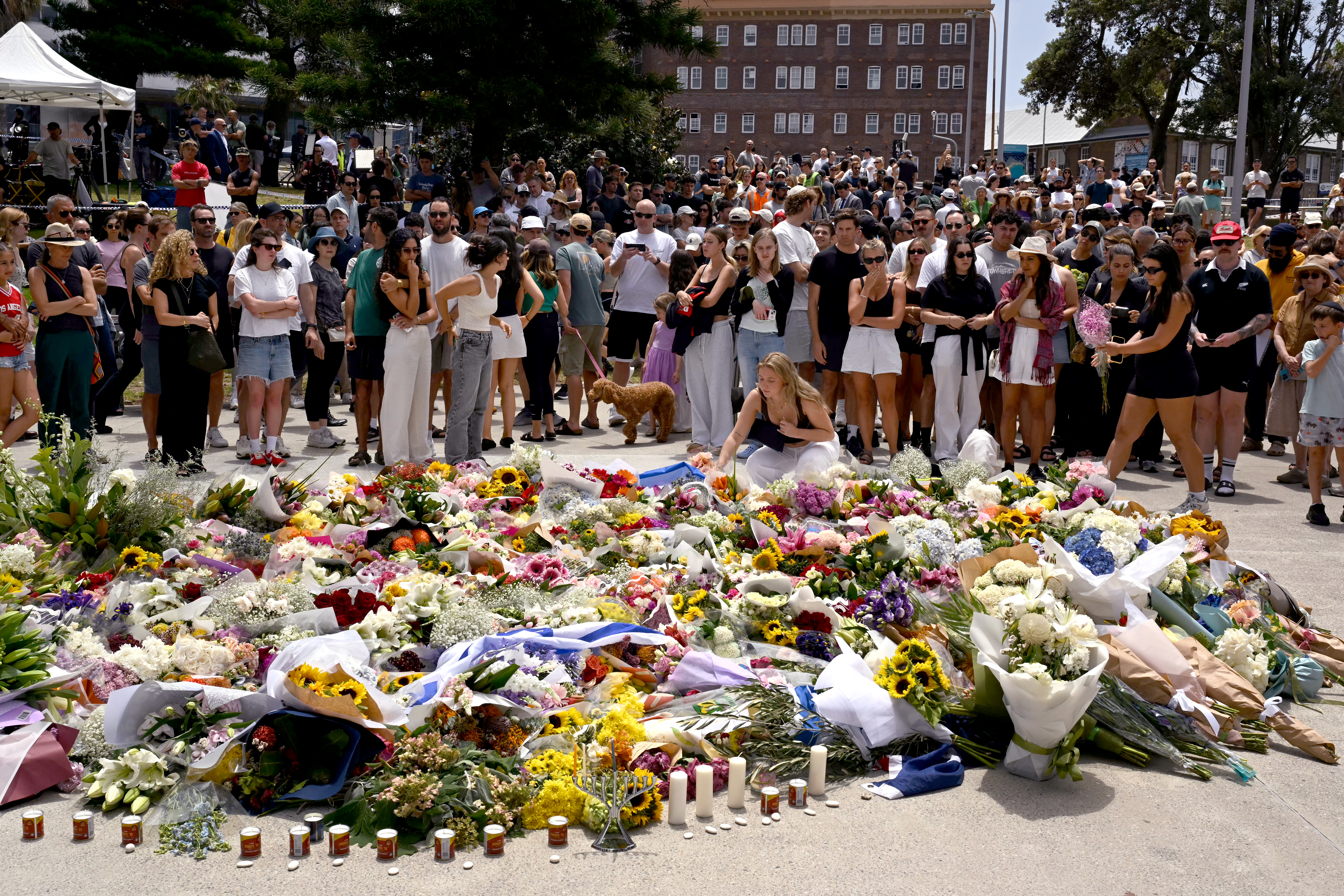 Mourners gather by floral tributes at the Bondi Pavillion in memory of the victims of a shooting at Bondi Beach, in Sydney on December 15, 2025.