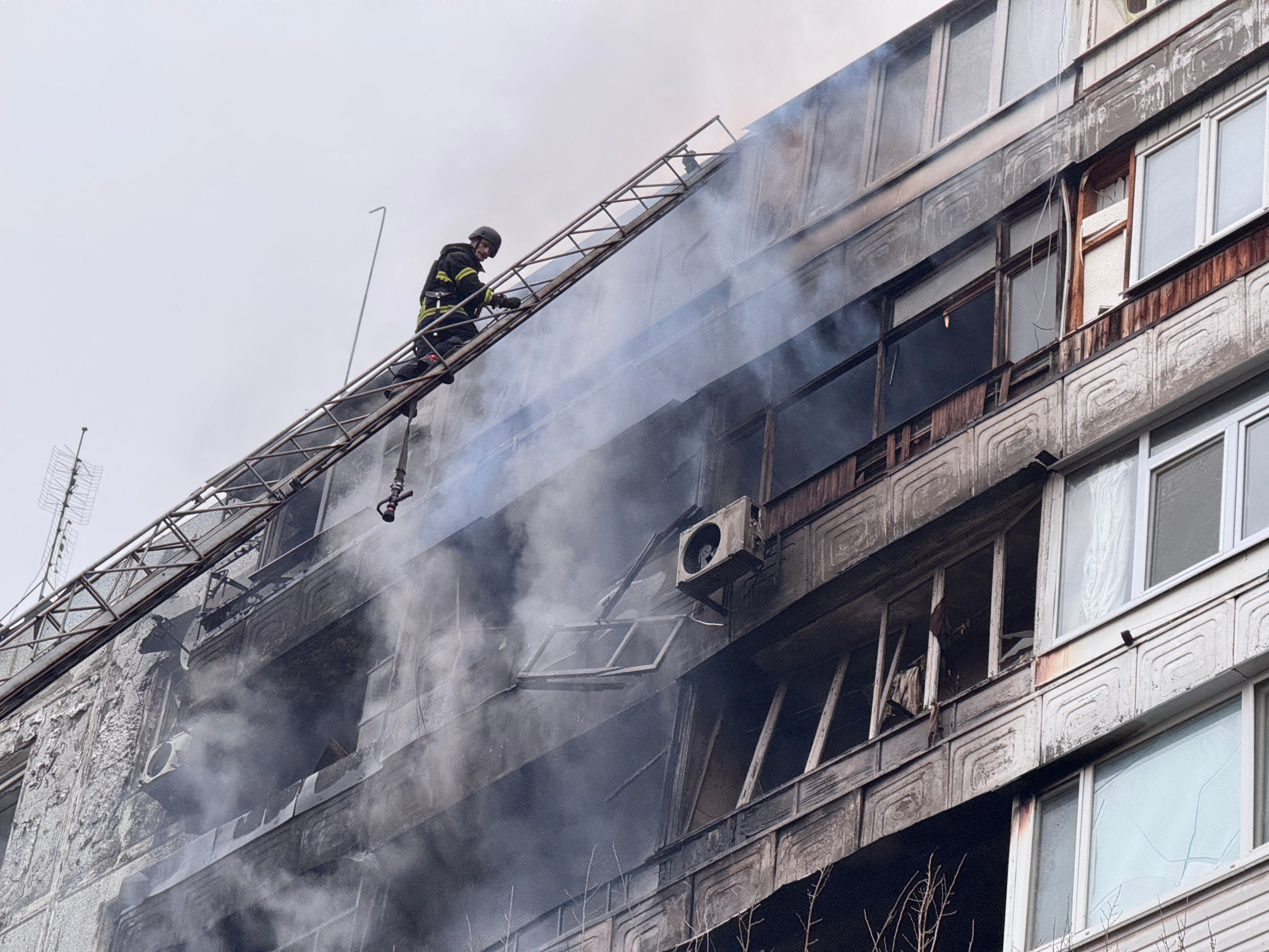 A firefighter climbs a ladder to the damaged residential building following an air attack in Zaporizhzhia on December 16, 2025, amid the Russian invasion of Ukraine. (Photo by Darya Nazarova (STR Zaporizhzhia) / AFP)