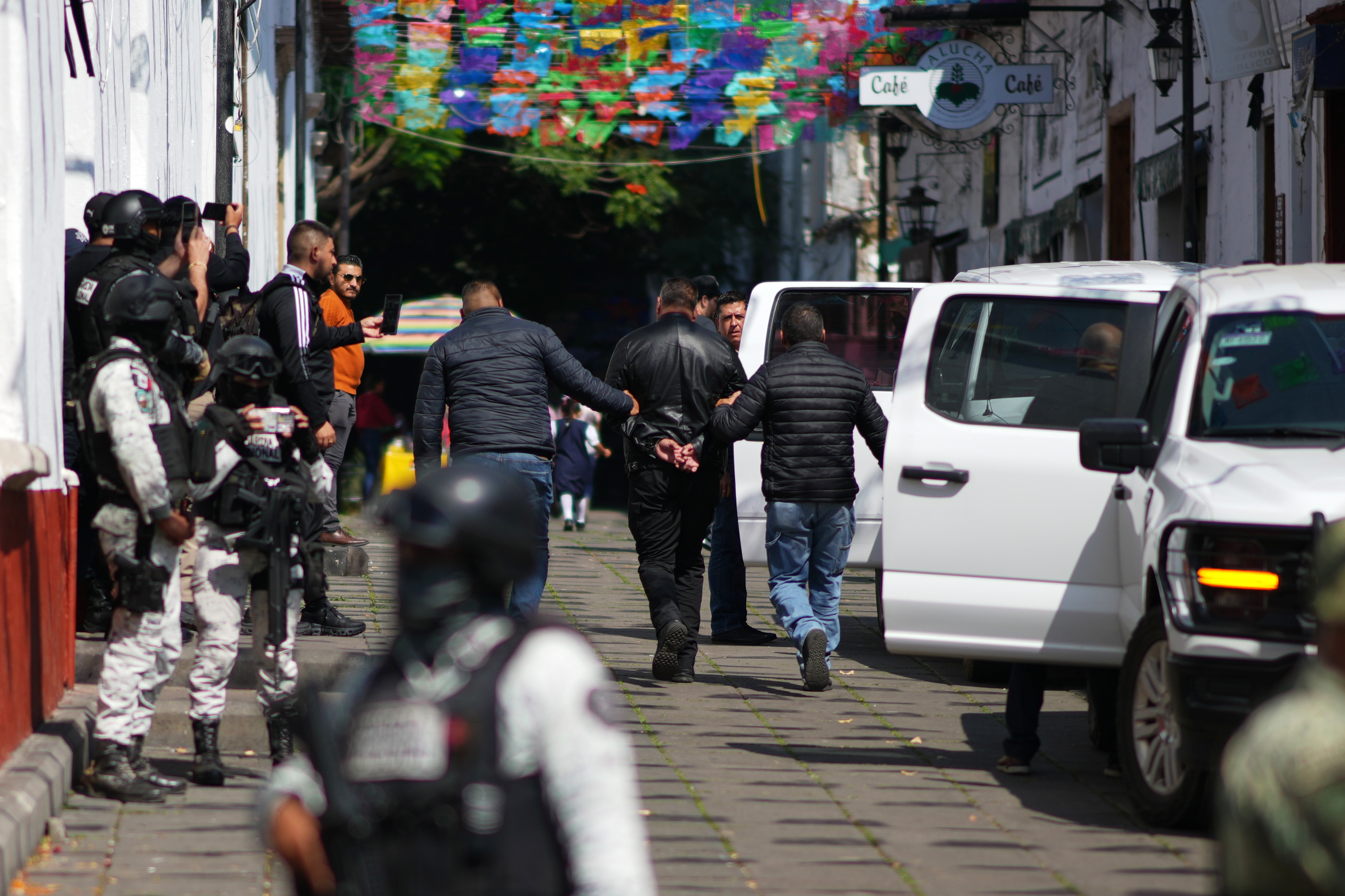 Officers detain a suspect in a street.