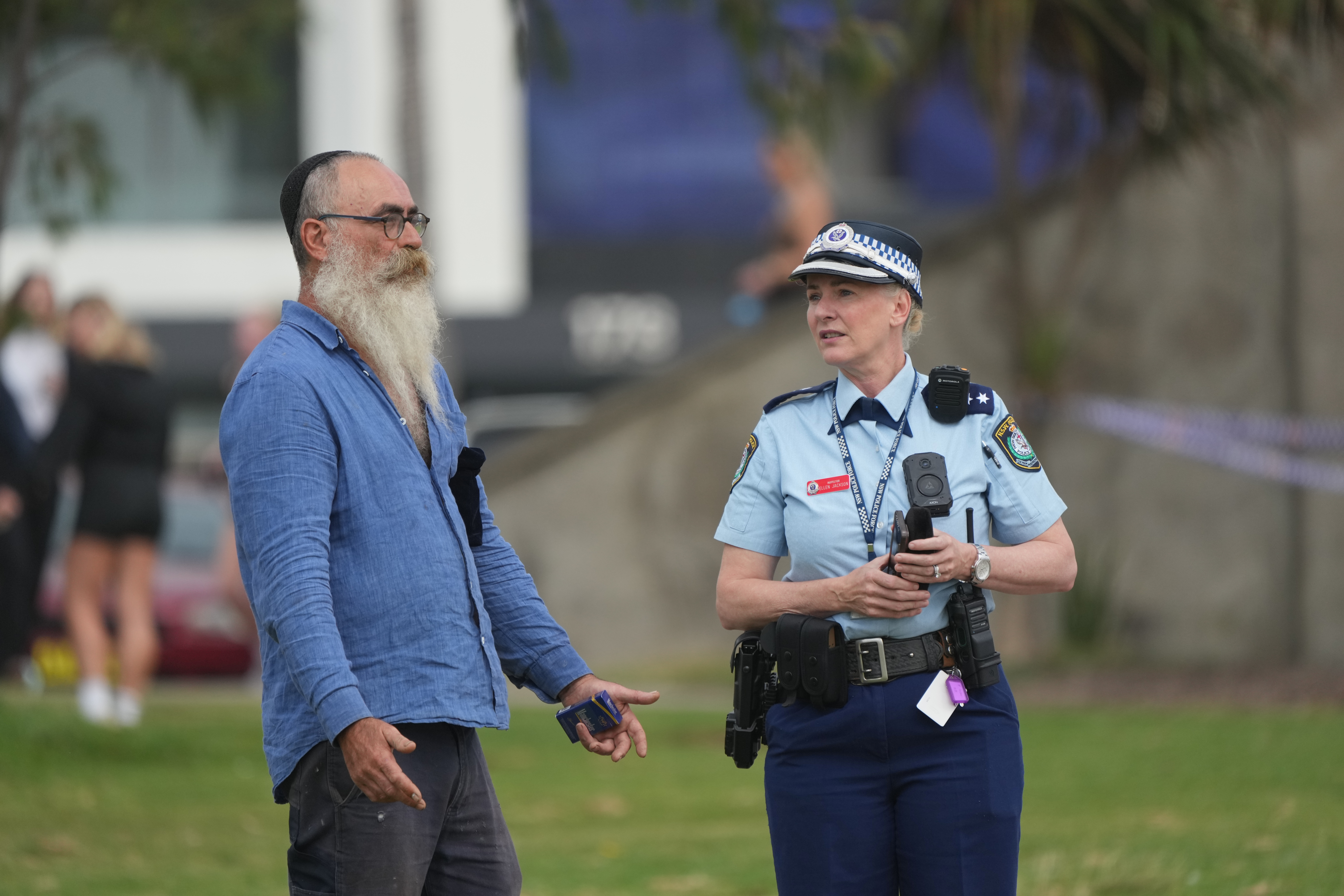 A police officer talks to a member of the public following a shooting the day prior at Sydney's Bondi Beach, Monday, Dec. 15, 2025. (AP Photo/Mark Baker)