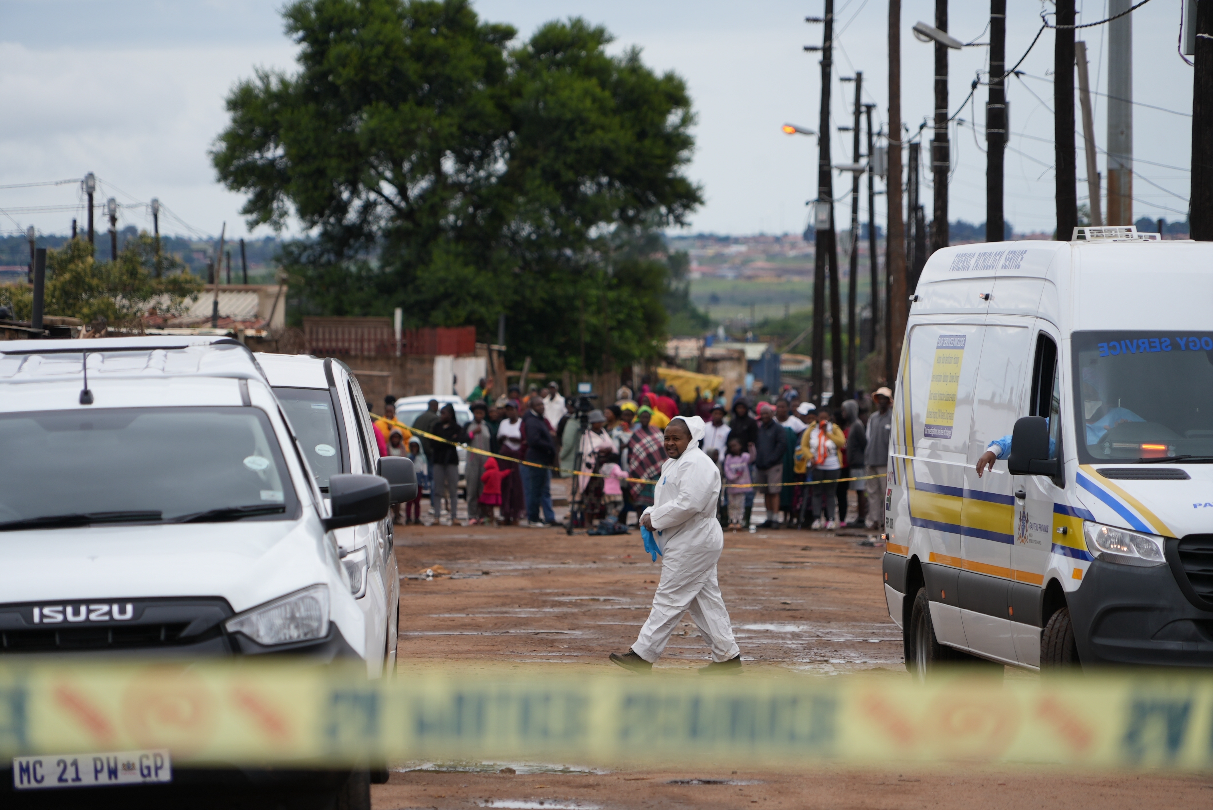 Onlookers gather at the scene of a mass shooting where gunmen killed nine and injured at least 10 in a pub in Bekkersdal, South Africa, Sunday, Dec. 21, 2025. (AP Photo/ Alfonso Nqunjana)