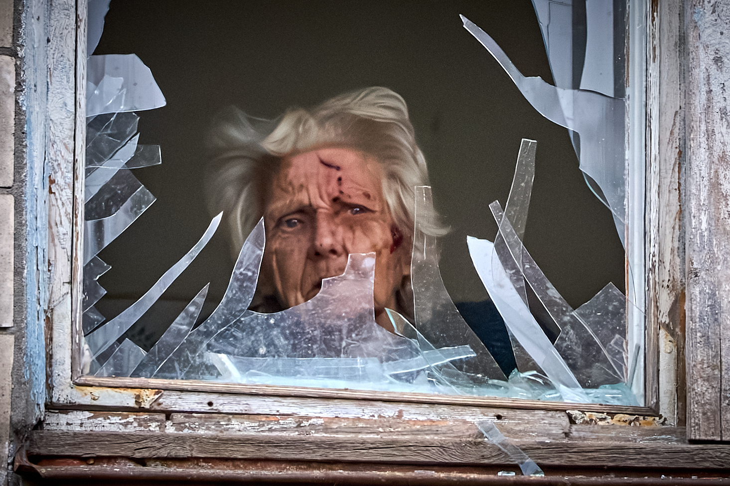 An injured elderly woman looks out of her broken window as an apartment building was hit by a Russian drone during an aerial attack in Kyiv, Ukraine, Tuesday, Dec. 23, 2025. (AP Photo/Efrem Lukatsky)