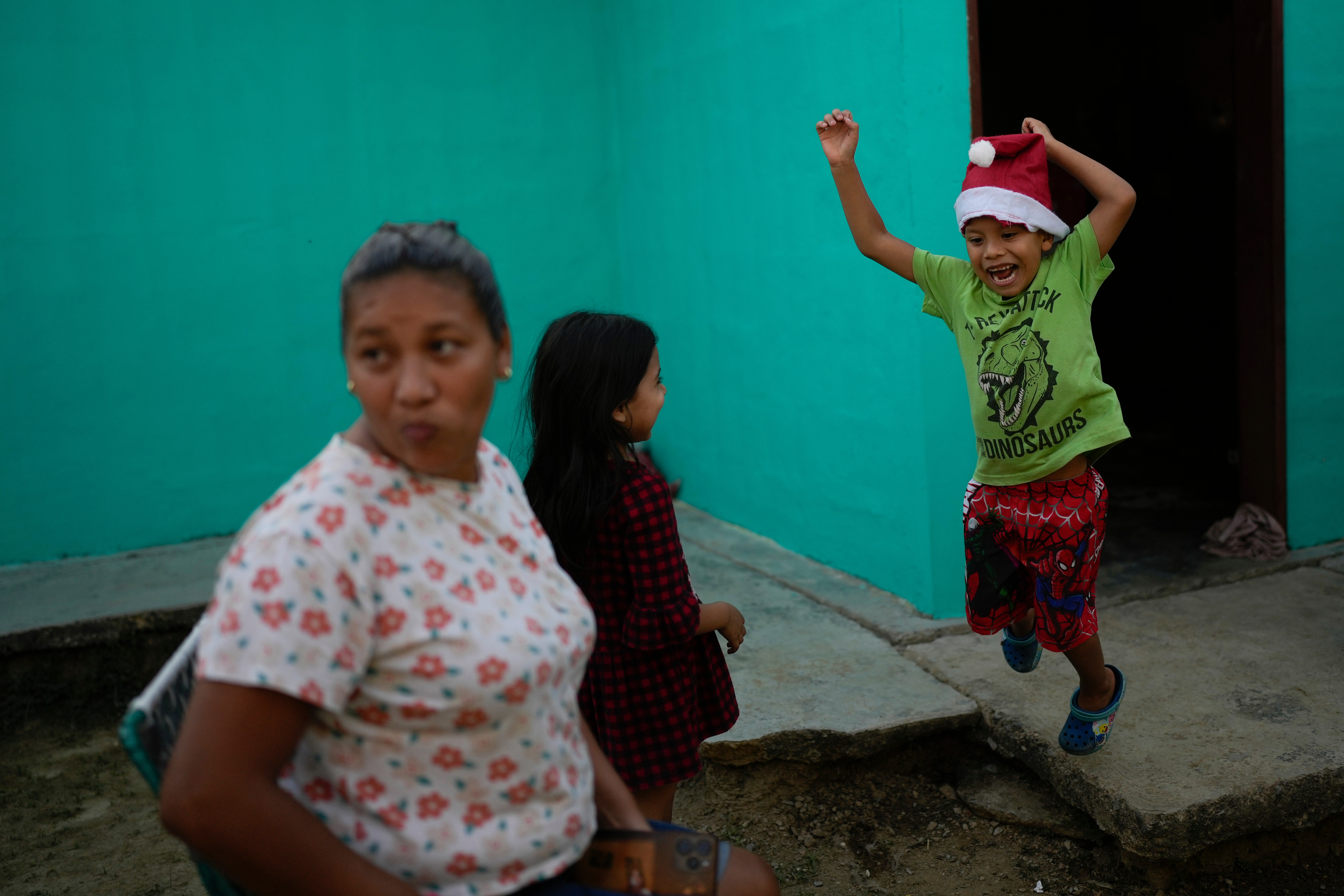 Mathias jumps after receiving a Christmas present from his mother, Mariela Gómez, left, in Maracay, Venezuela, Wednesday, Dec. 24, 2025. The two returned home after abandoning their journey to the United States following President Donald Trump's immigration crackdown. (AP Photo/Matias Delacroix)