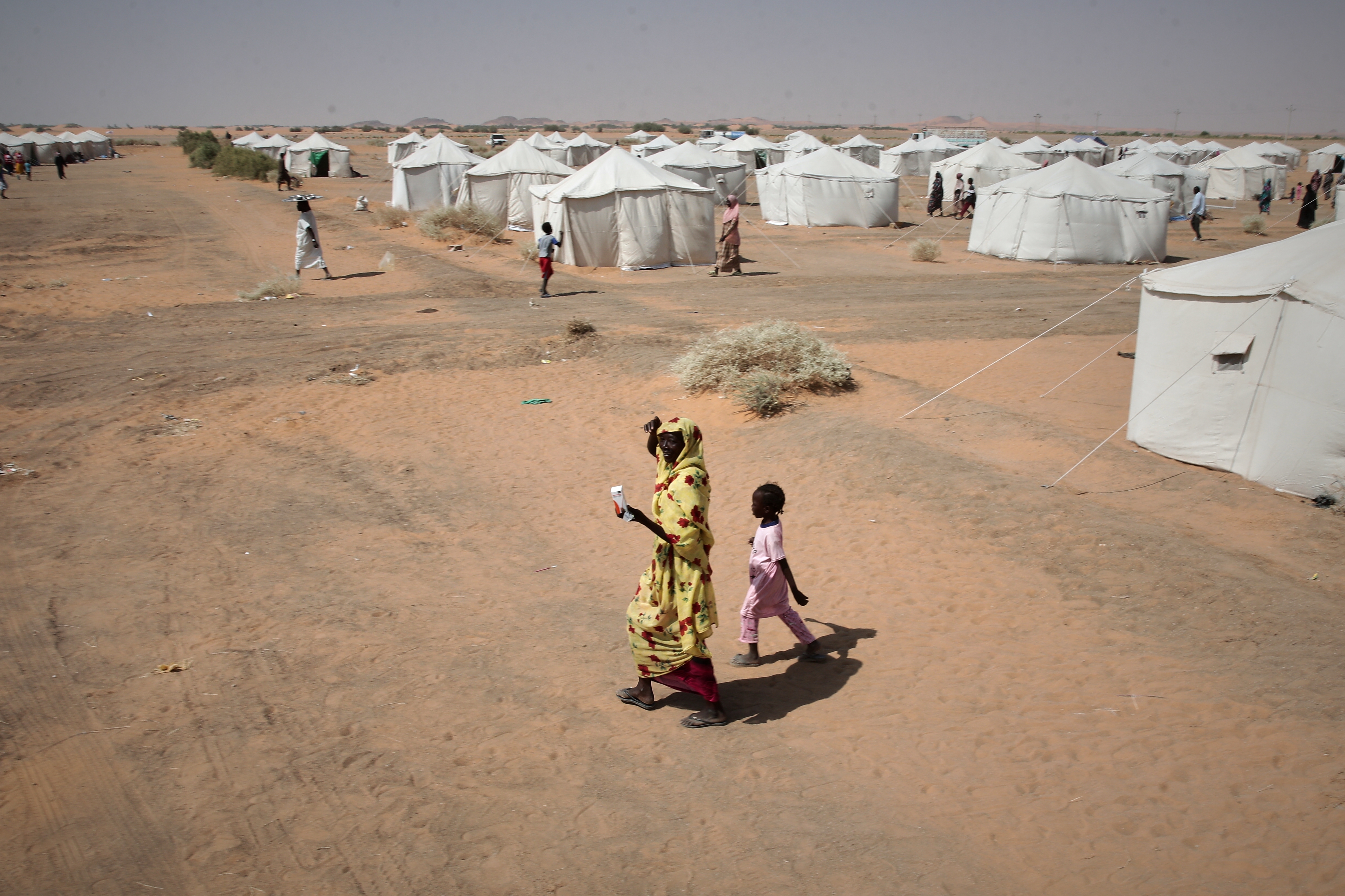 A woman and a child walk in a displacement camp.