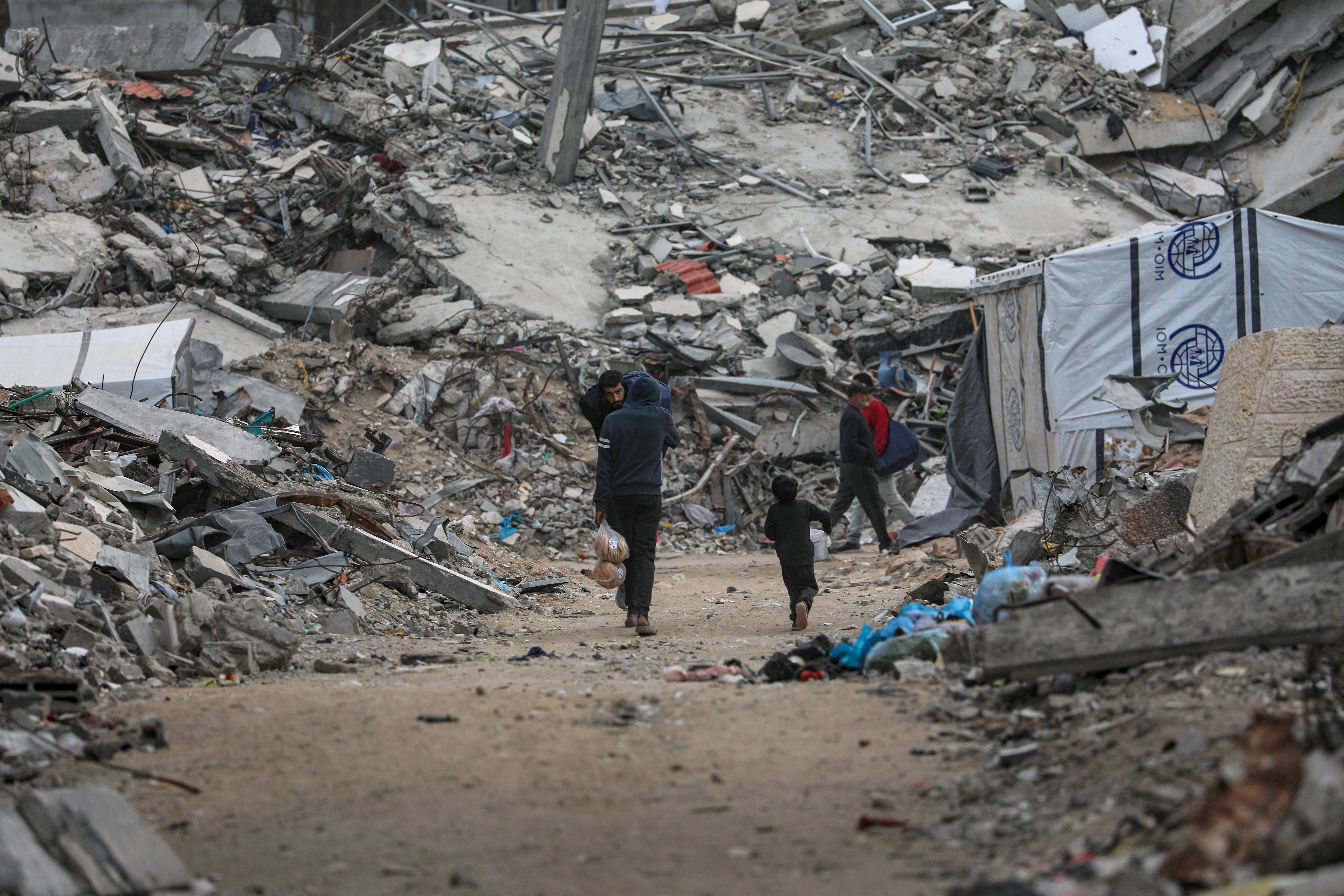epa12578943 Internally displaced Palestinians walk among the ruins of destroyed buildings in the Al Sheikh Radwan neighborhood of Gaza City, Gaza Strip, 08 December 2025, amid a ceasefire between Israel and Hamas. Around 1.9 million people in Gaza, nearly 90 percent of the population, have been displaced since the Israel-Hamas conflict began in October 2023, according to the UN. EPA/MOHAMMED SABER