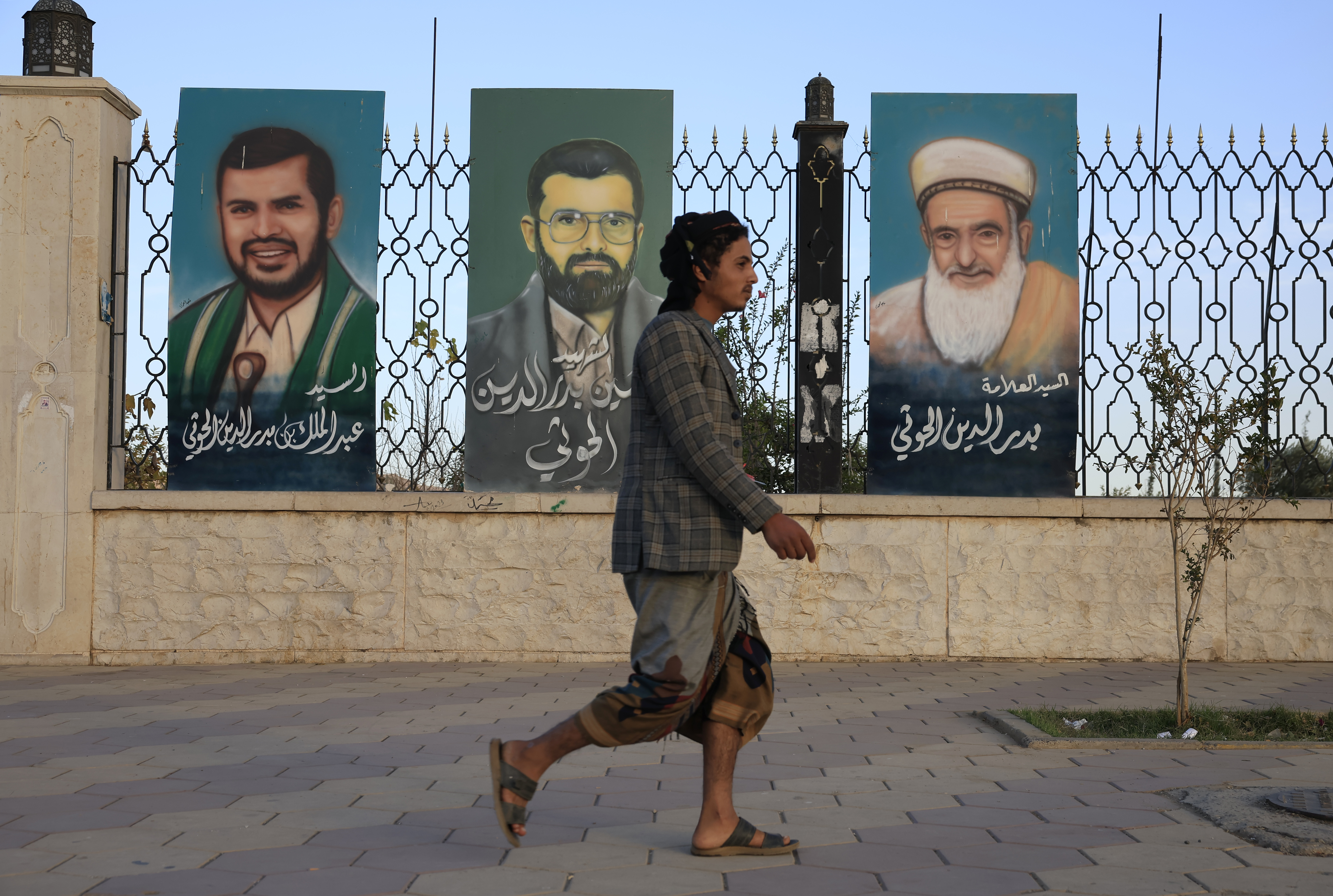 epa12579080 A person walks past paintings on a fence depicting senior Houthi leaders, in Sana'a, Yemen, 08 December 2025. The Yemeni government has announced in a statement that a new round of UN-sponsored talks with the Houthis will be held next week in Oman, as part of a fresh effort to secure the release of hundreds of war prisoners. This comes nearly five years after about 1,000 prisoners from both sides were released, marking the largest exchange since the conflict began in 2014. EPA/YAHYA ARHAB