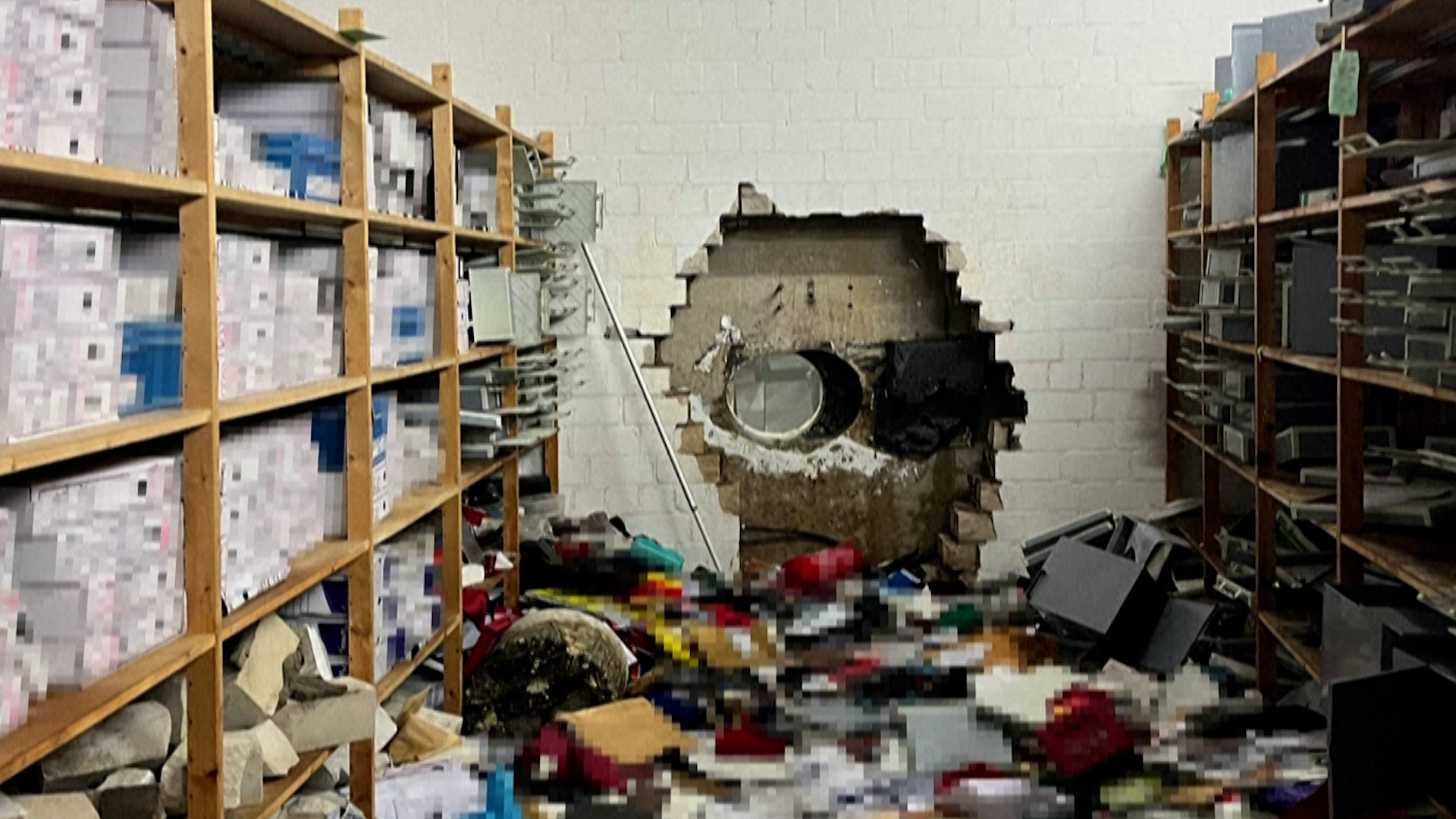 A police handout photo shows a hole in the vault wall at Sparkasse bank after a robbery on December 29, 2025. Personal belongings visible in the image have been pixelated by police. [Gelsenkirchen Police/Reuters]