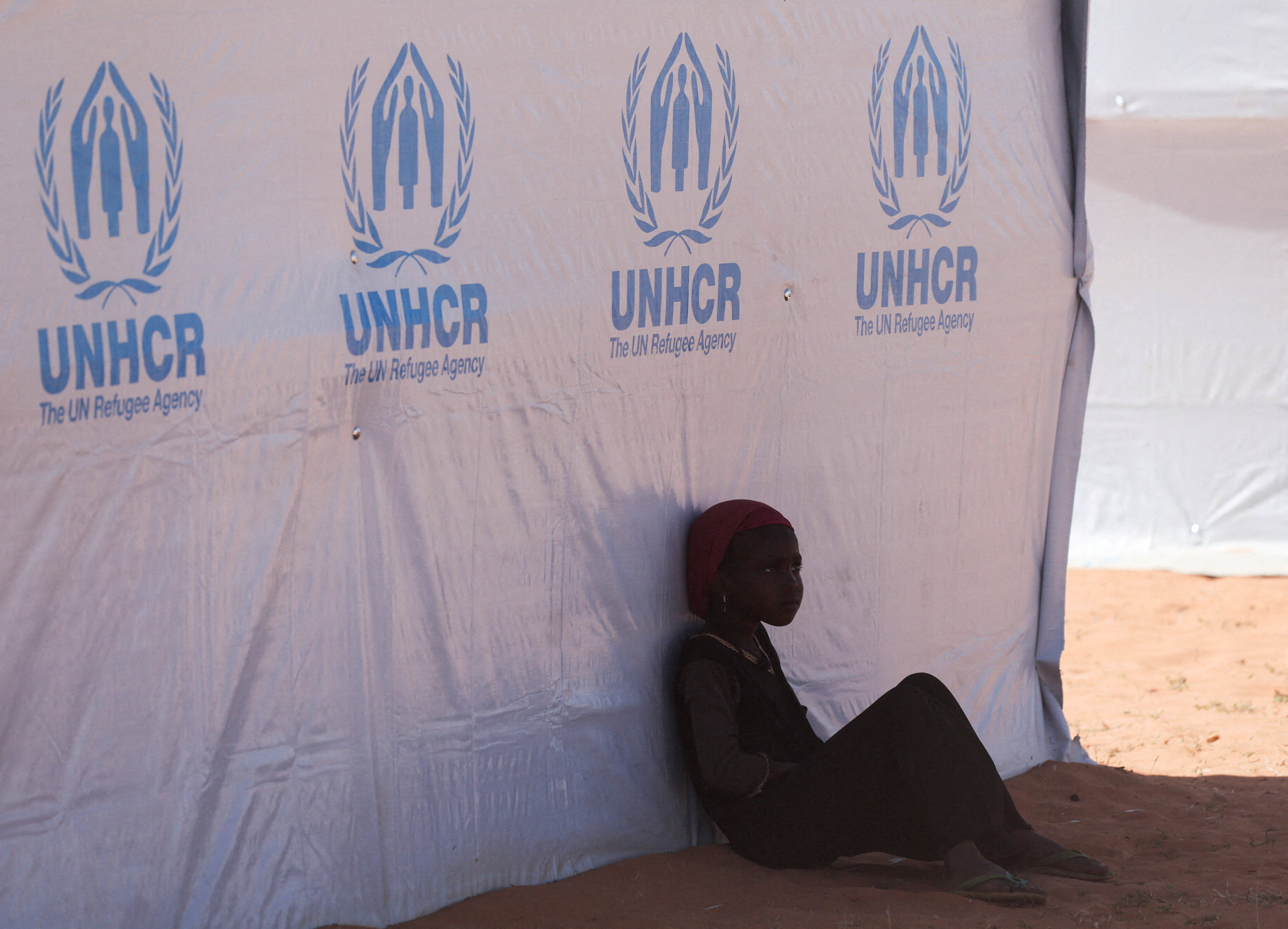 A Sudanese refugee girl from Darfur rests beside a United Nations High Commissioner for Refugees (UNHCR) tent inside the Touloum refugee camp, amid ongoing conflict in their country, on the outskirts of the town of Iriba in Wadi Fira province, eastern Chad, November 30, 2025. REUTERS/Amr Abdallah Dalsh