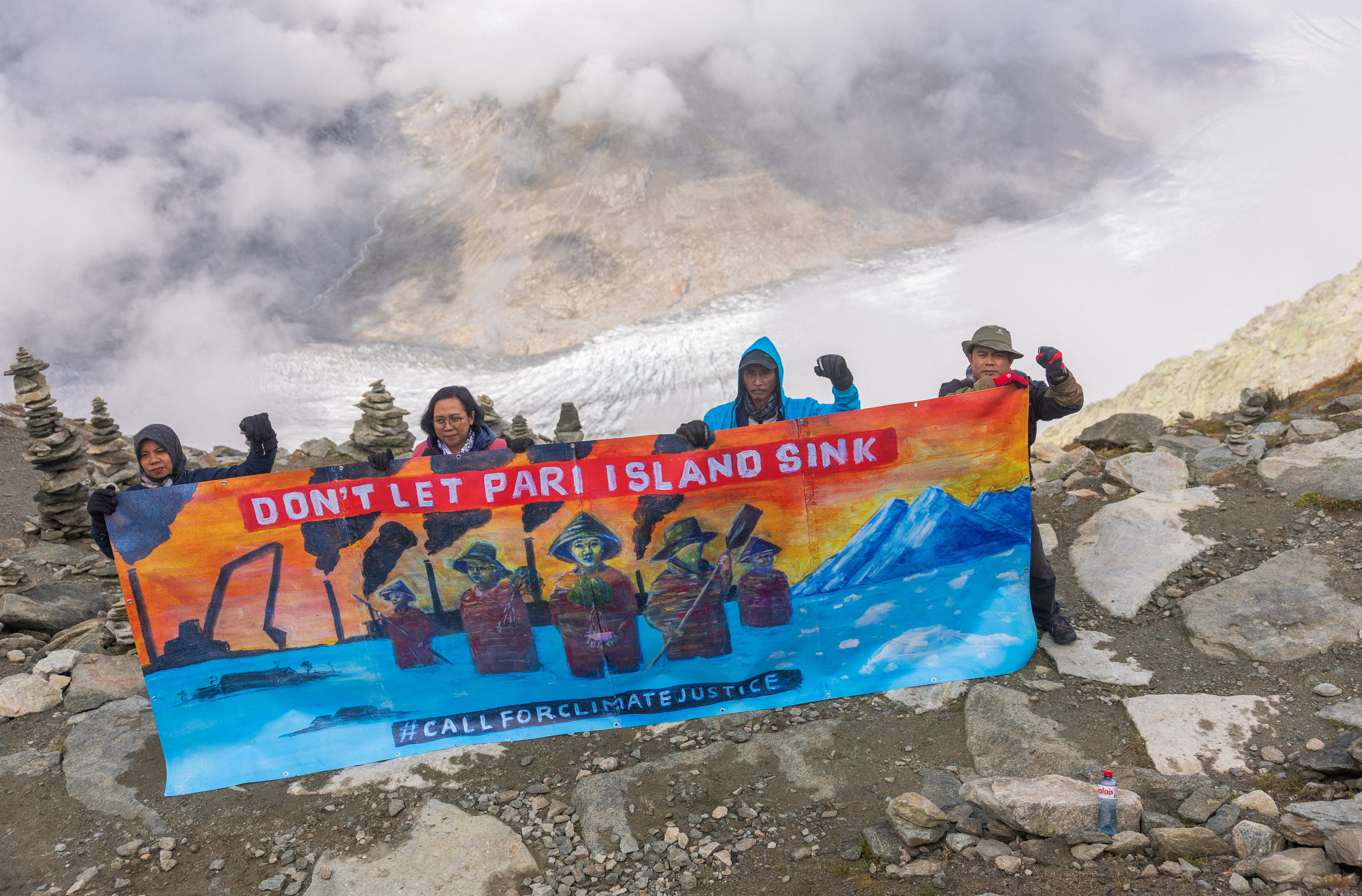 Ibu Asmania and Arif Pujianto, residents of Indonesia's Pari Island, hold a banner on Eggishorn mountain