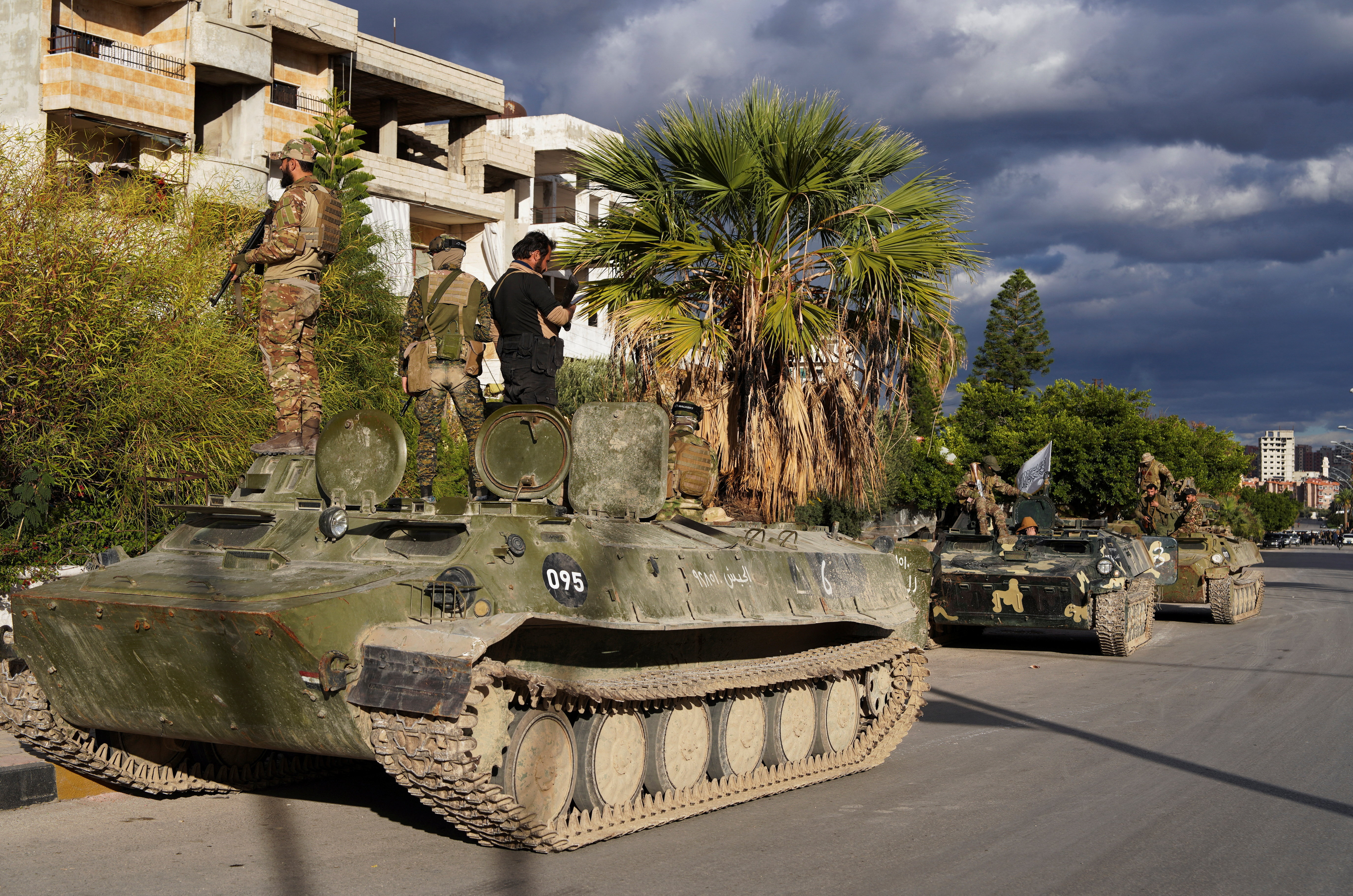 Members of the Syrian Security forces stand atop a military vehicle on the day people from the Alawite sect protest as they demand federalism and an end to what they say is the killing and violations against Alawites, in Latakia, Syria, December 28, 2025. REUTERS/Karam al-Masri