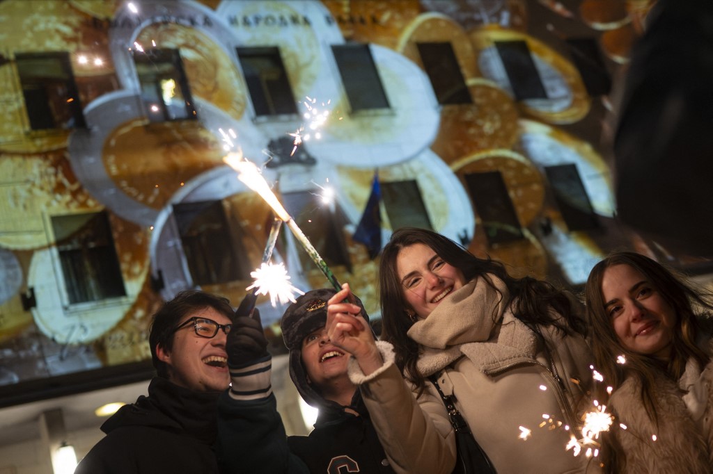 Revellers light sparklers as they celebrate the New Year in front of the Bulgarian National Bank as Bulgaria officially adopts the euro, in Sofia, on January 1, 2026. Bulgaria became the 21st country to switch to the euro as it entered the New Year on January 1, 2026, a milestone met with both cheers and fears, nearly 20 years after the Balkan nation joined the European Union. (Photo by Nikolay DOYCHINOV / AFP)