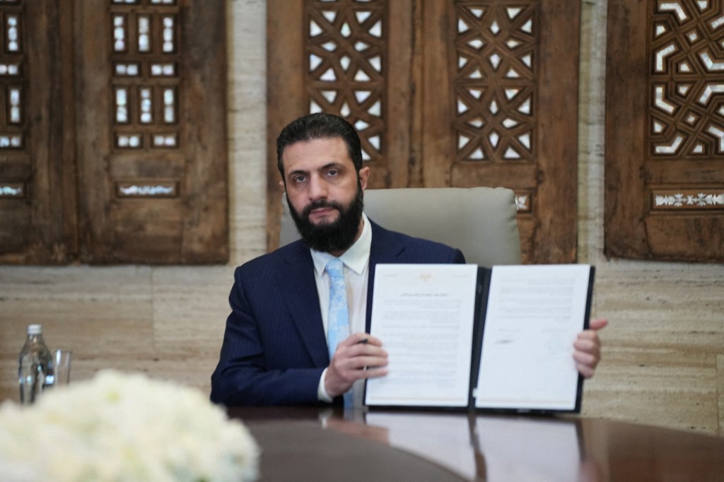 Syria's President Ahmed al-Sharaa signs an agreement at the Presidential Palace in Damascus on January 18, 2026. Syrian President Ahmed al-Sharaa on January 18, announced an agreement with the chief of the Kurdish-led Syrian Democratic Forces that includes a ceasefire after government forces advanced in Kurdish-held areas of the north and east.