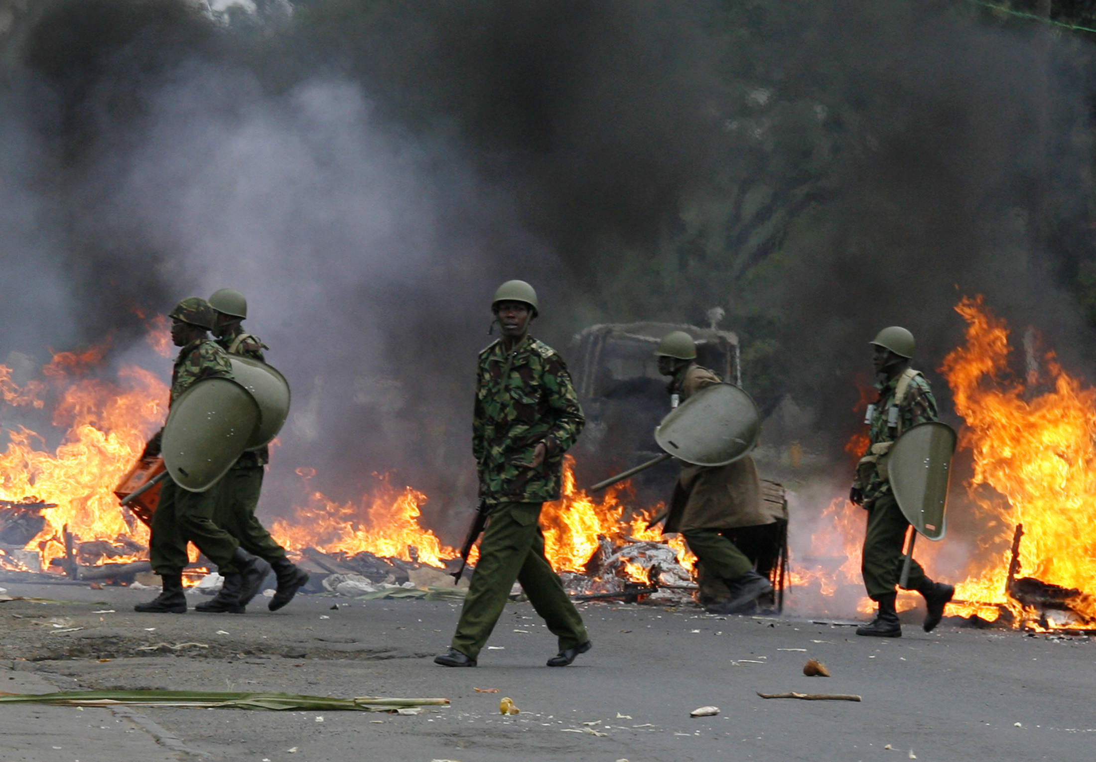 Riot police move to dismantle a burning roadblock in Nairobi December 31, 2007. Kenyan police fired teargas and shots in the air to disperse youths protesting in a Nairobi slum on Monday against a disputed election that handed President Mwai Kibaki a second term in office, witnesses said. REUTERS/Noor Khamis (KENYA)