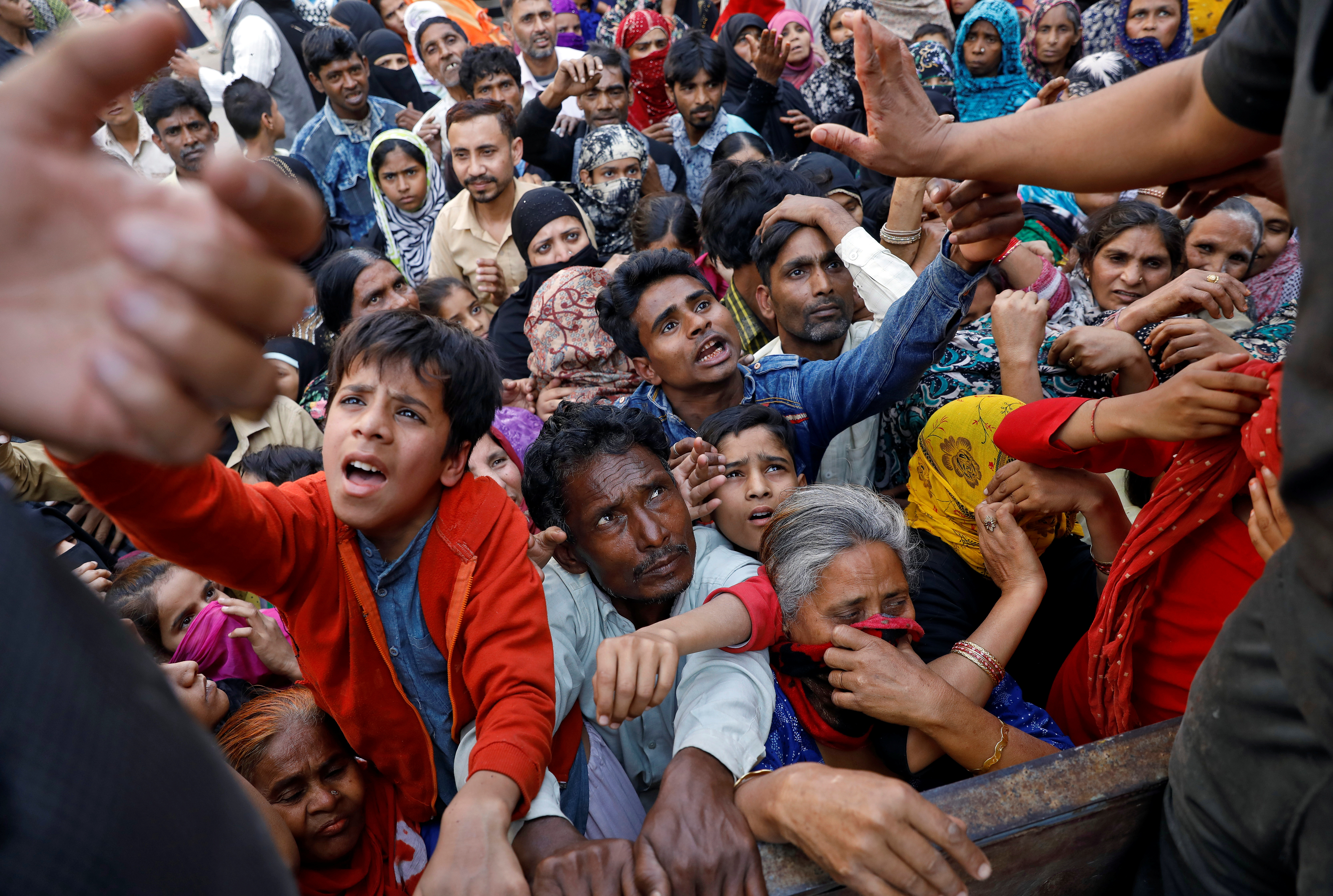 People crowd to receive free grocery items being distributed outside a relief camp after fleeing their homes following Hindu-Muslim clashes triggered by a new citizenship law, in Mustafabad in the riot-affected northeast of New Delhi, India, March 3, 2020