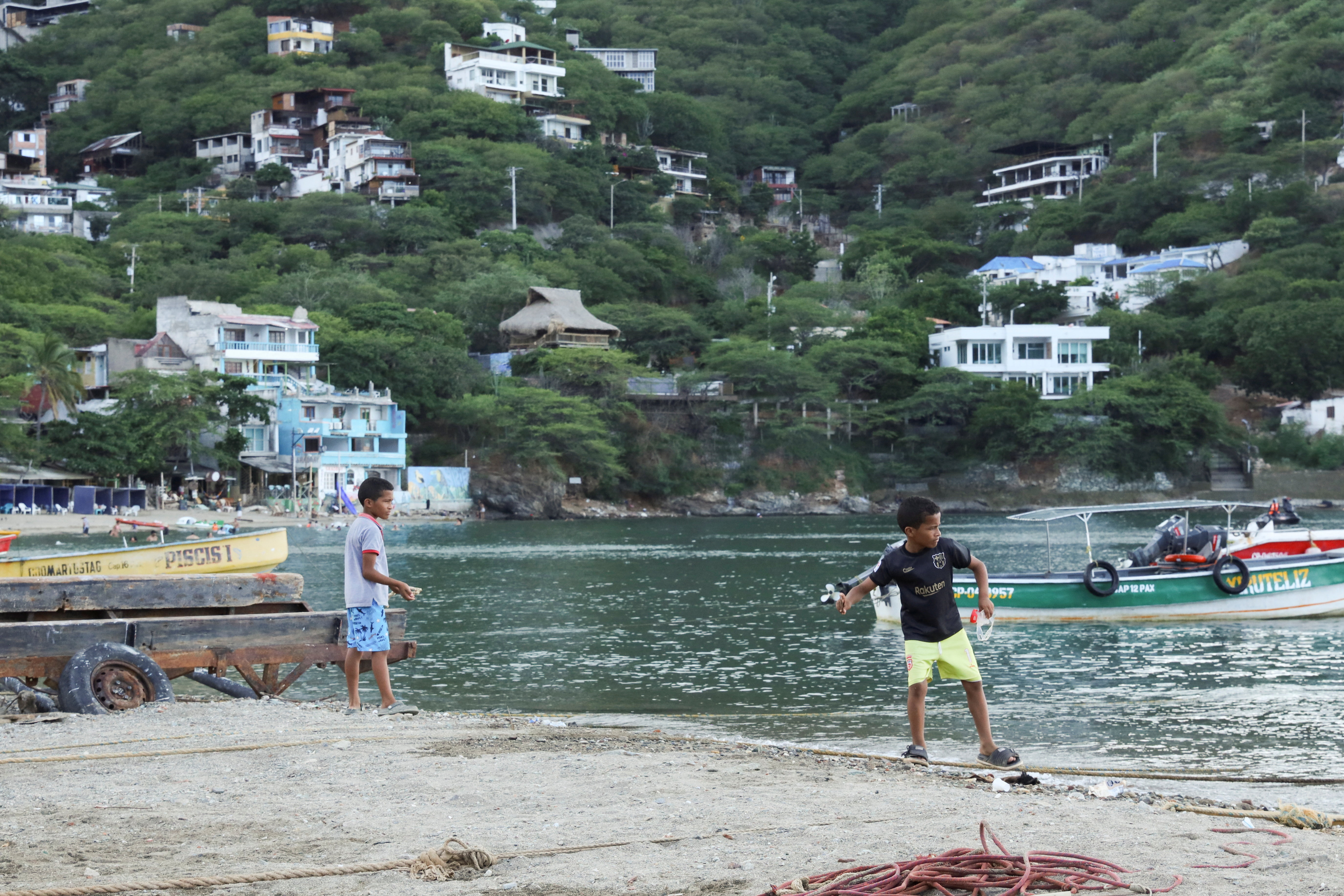 Children play on Taganga Beach, near fishing boats